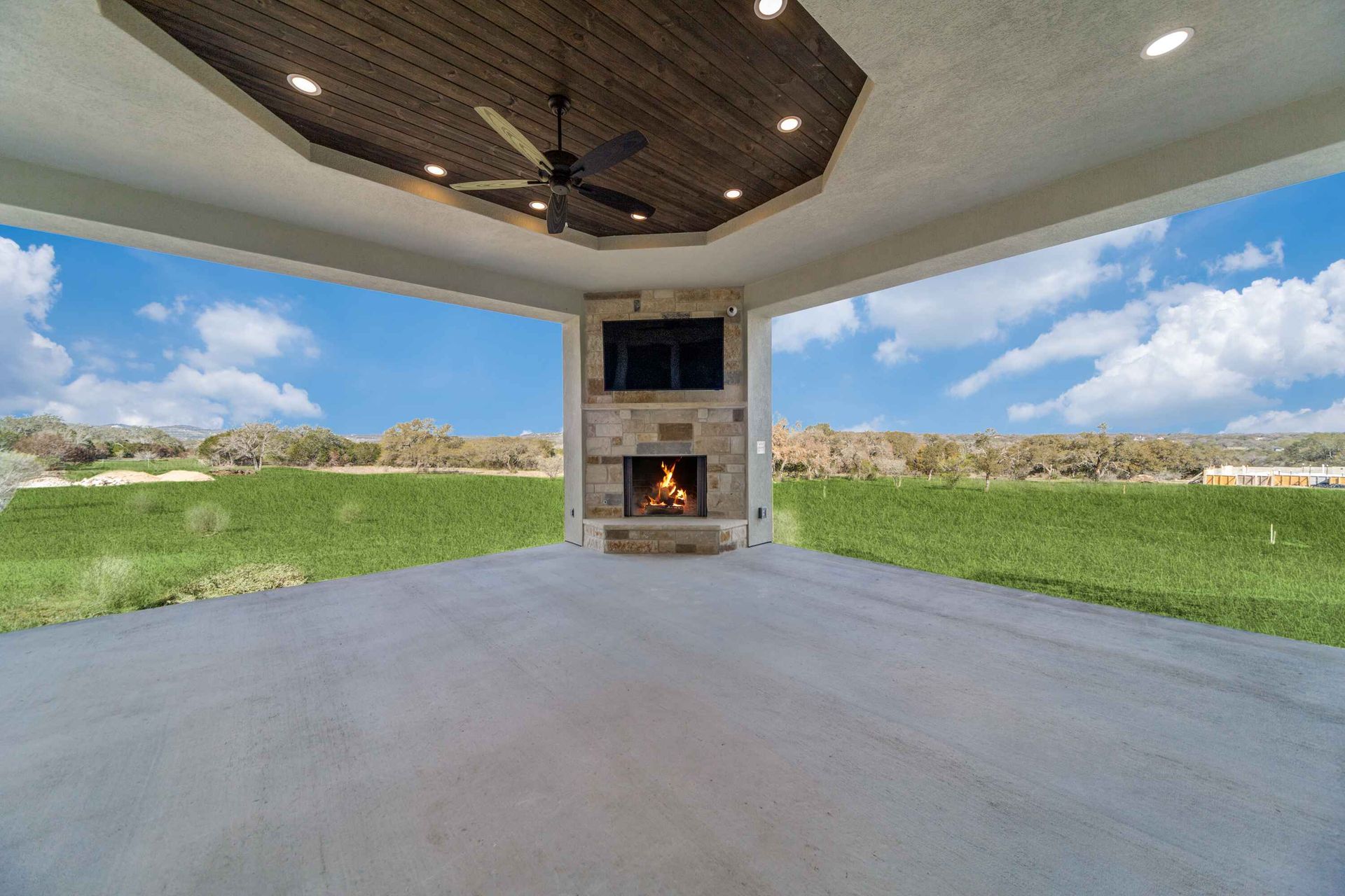 A large patio with a fireplace and a ceiling fan.