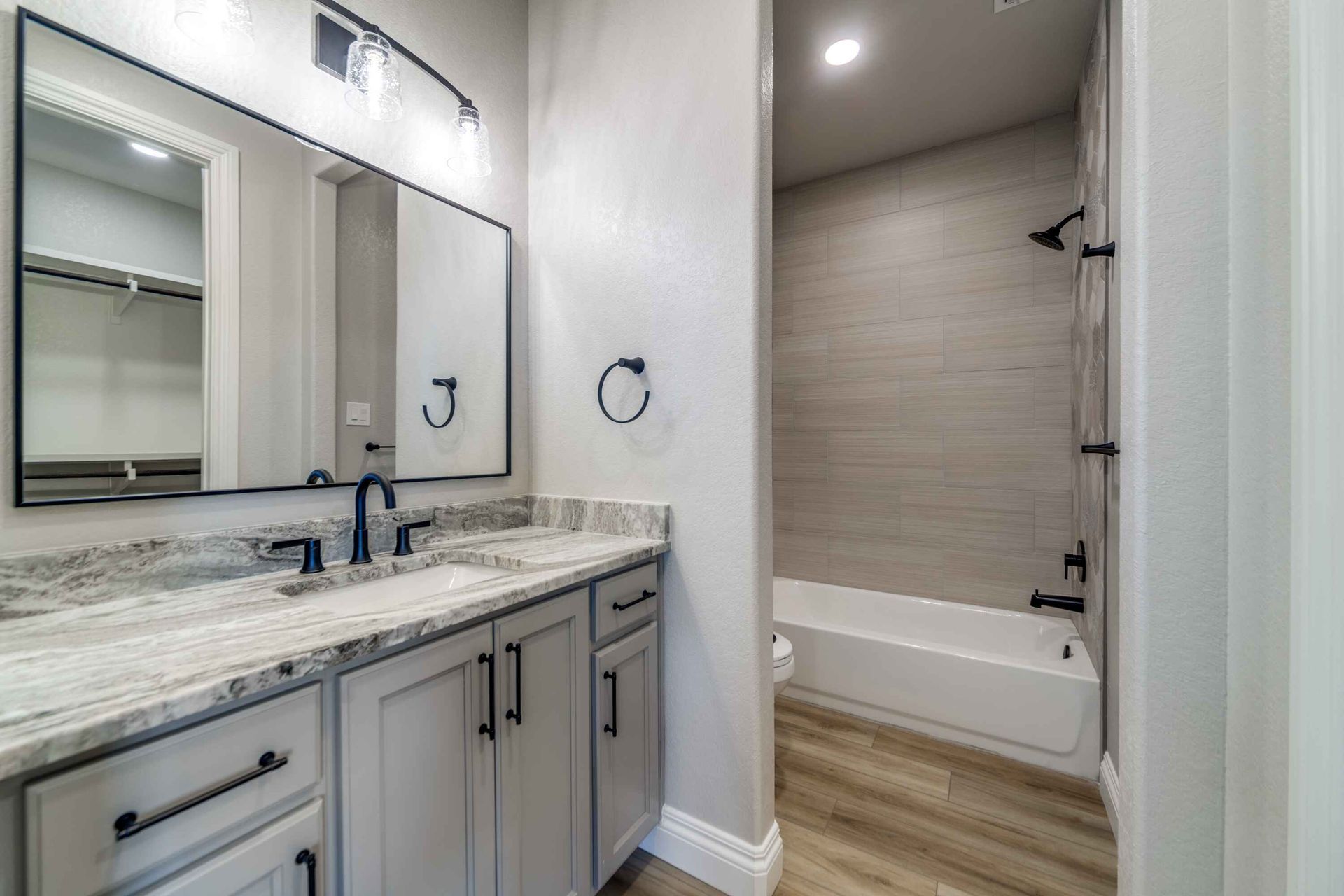 A bathroom with two sinks , a tub , and a mirror.