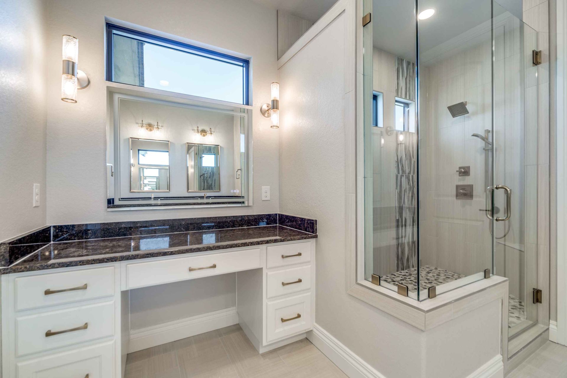 A bathroom with a walk in shower and a vanity.