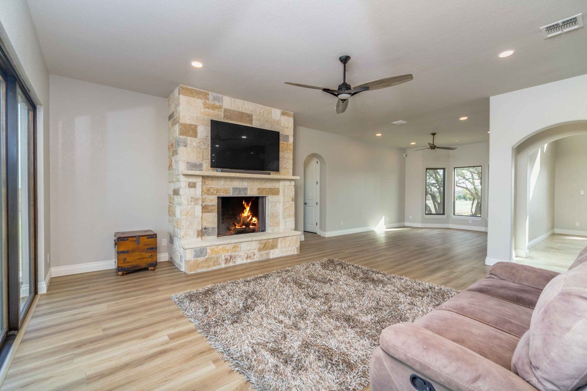 A living room with a couch , fireplace , television and ceiling fan.