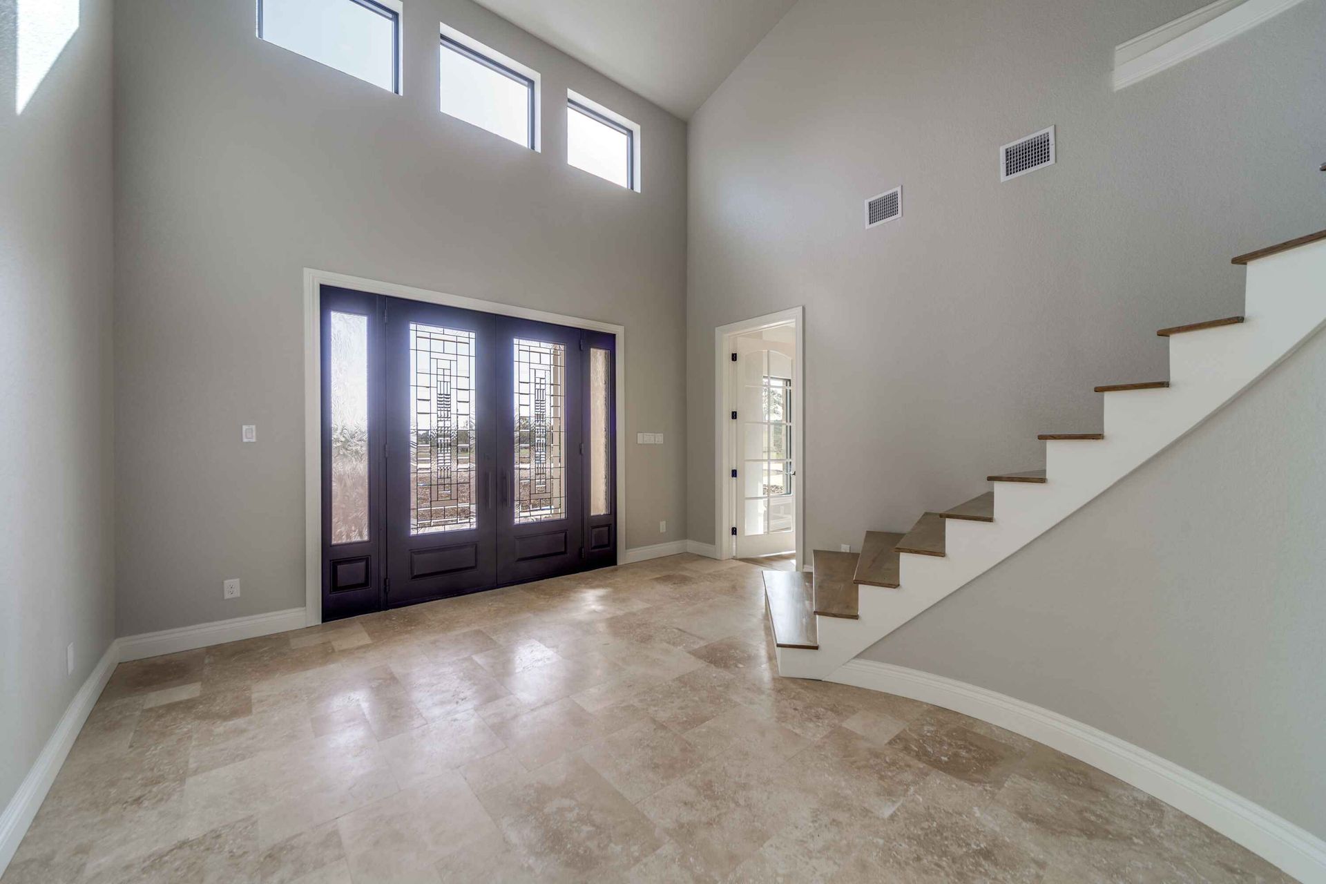An empty living room with stairs leading up to the second floor.