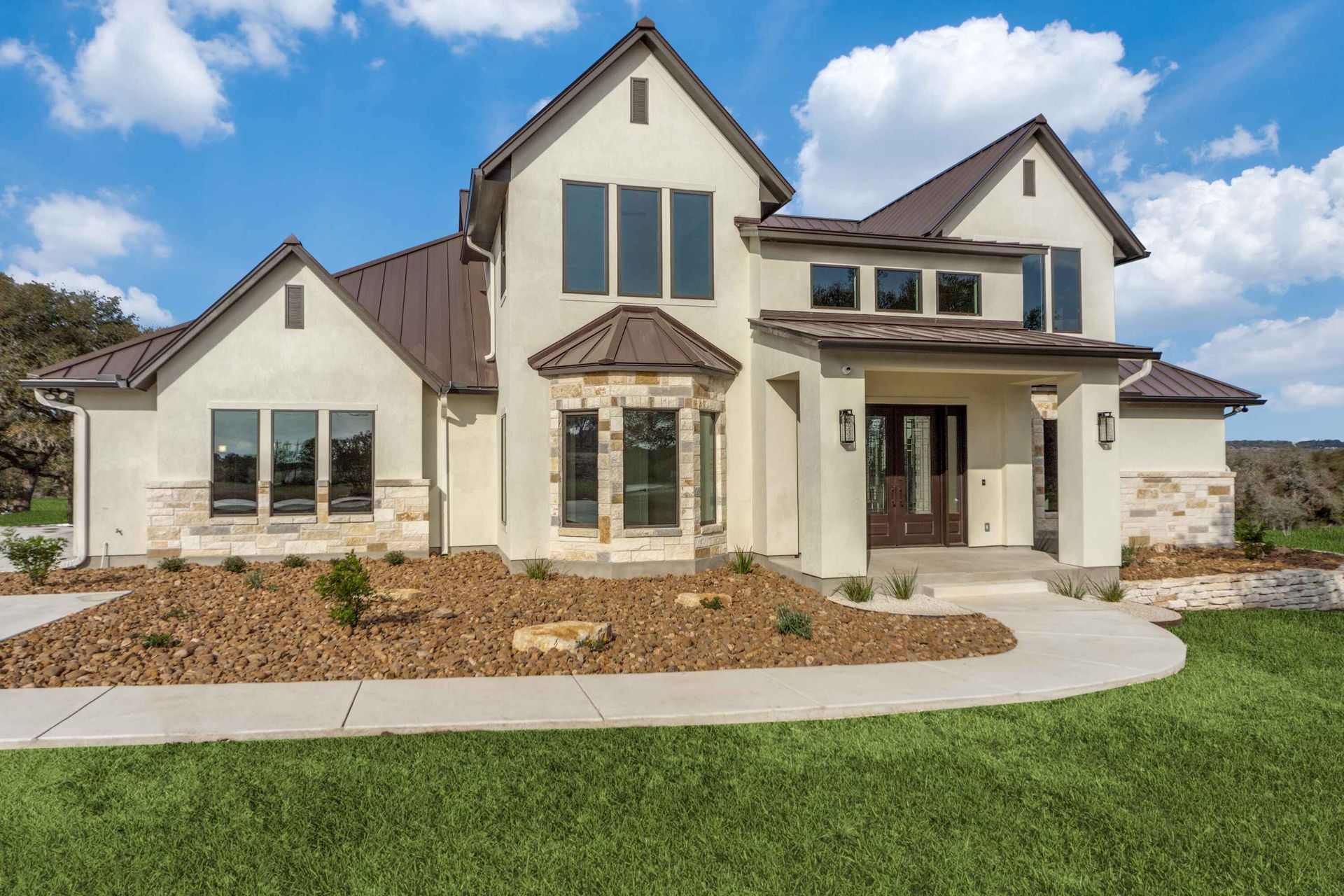 A large white house with a brown roof is sitting on top of a lush green field.