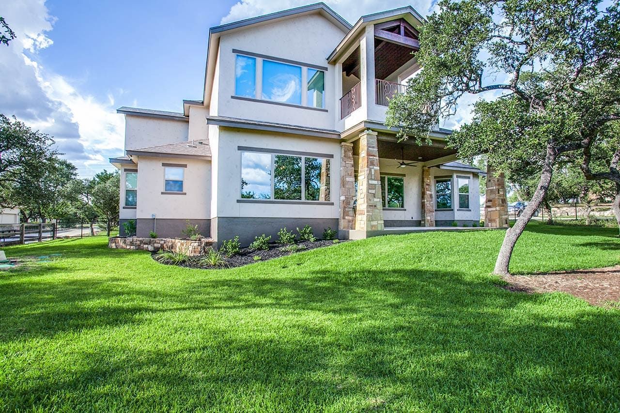 A large white house with a lot of windows is sitting on top of a lush green hill.