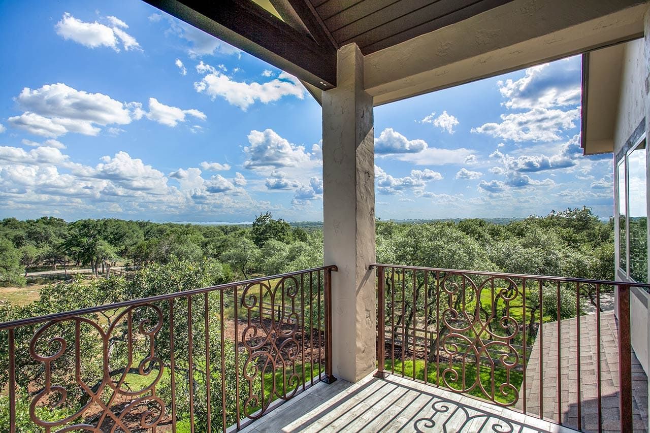 A balcony with a view of a forest and a blue sky.