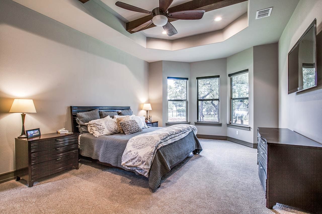 A bedroom with a bed , nightstands , a ceiling fan and a television.