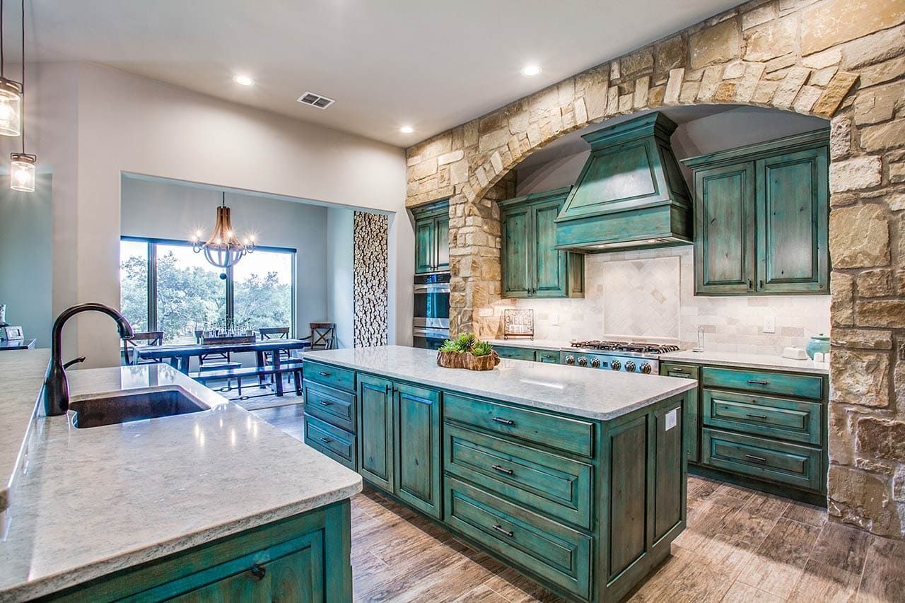 A kitchen with green cabinets , white counter tops , and a large island.