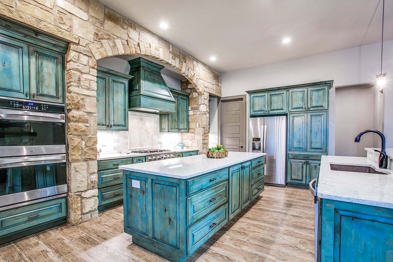 A kitchen with blue cabinets and a large island in the middle.