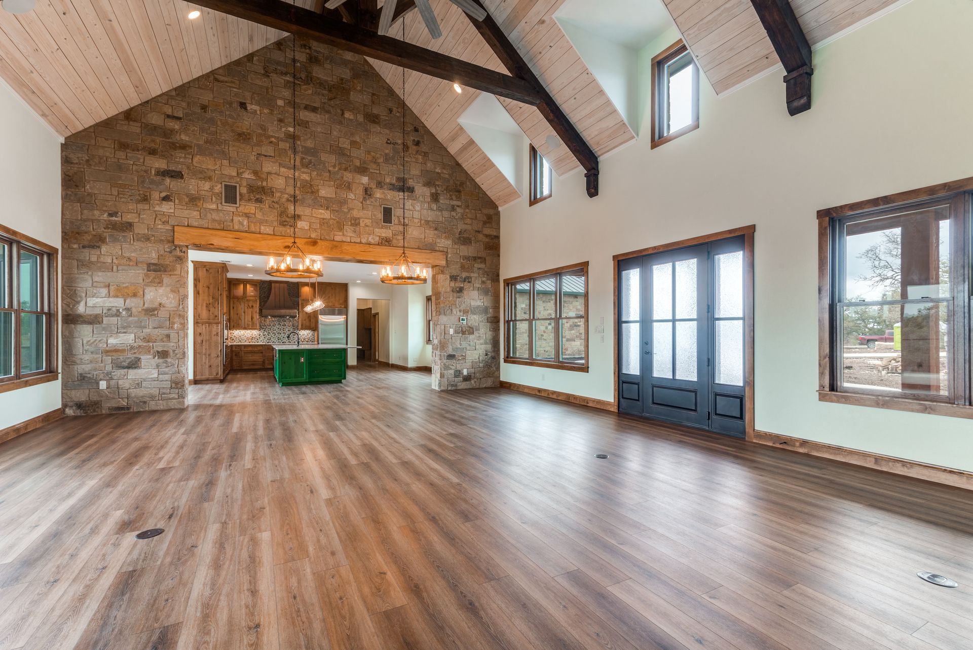 A large empty room with hardwood floors and a vaulted ceiling.