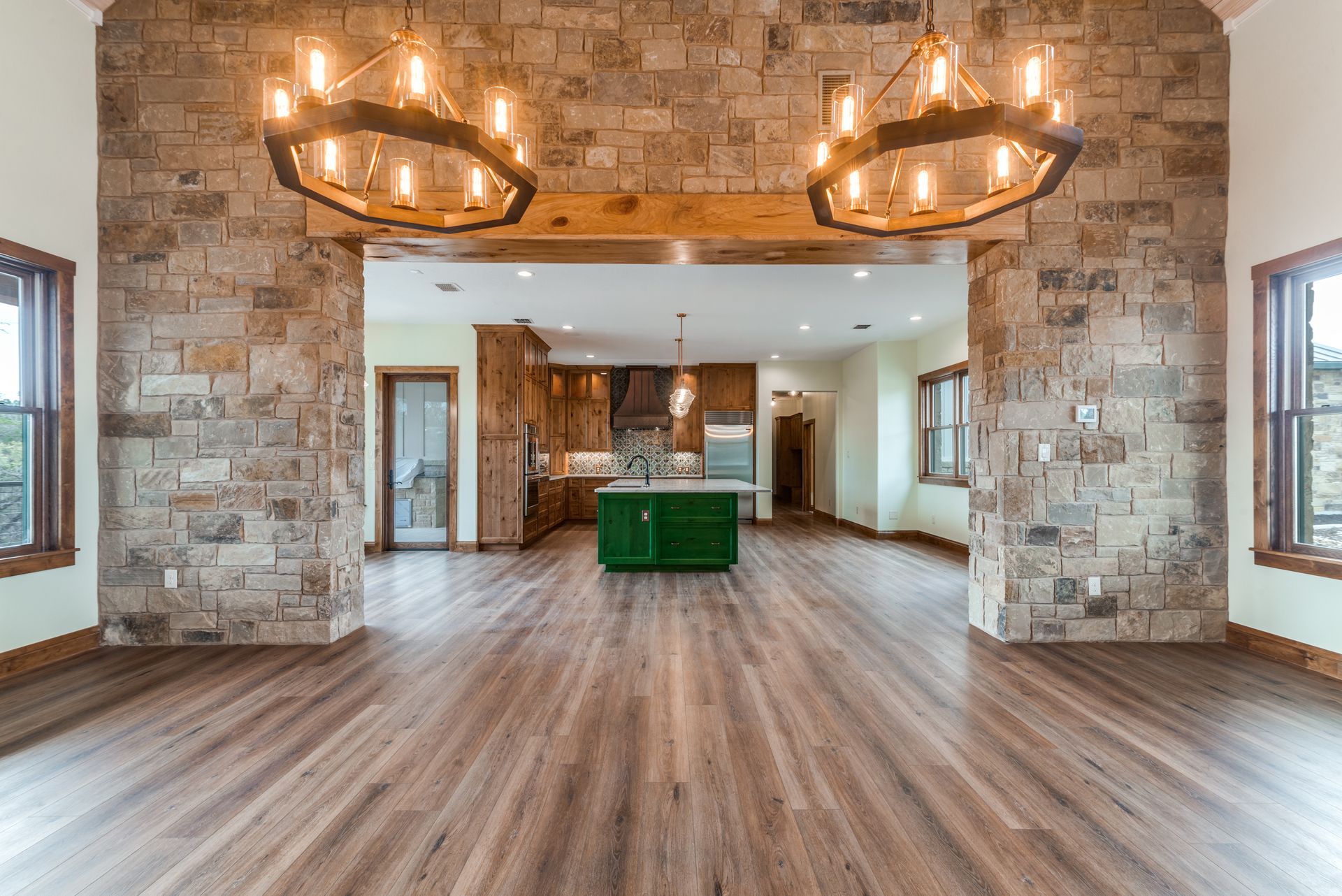 A large empty room with hardwood floors and a brick wall.