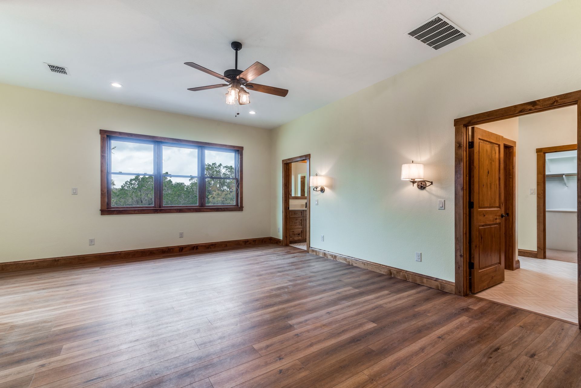 A large empty room with hardwood floors and a ceiling fan.