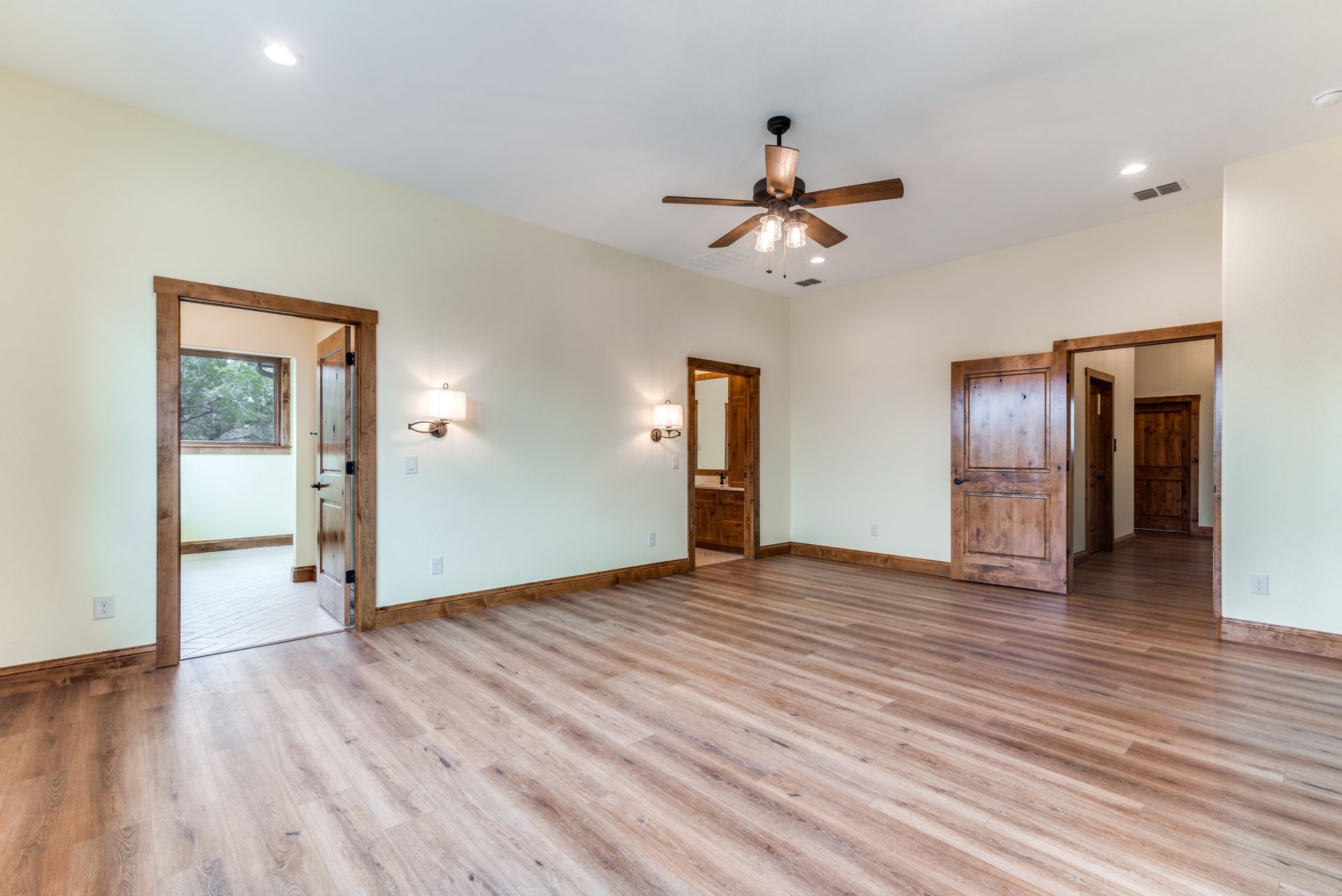 An empty living room with hardwood floors and a ceiling fan.