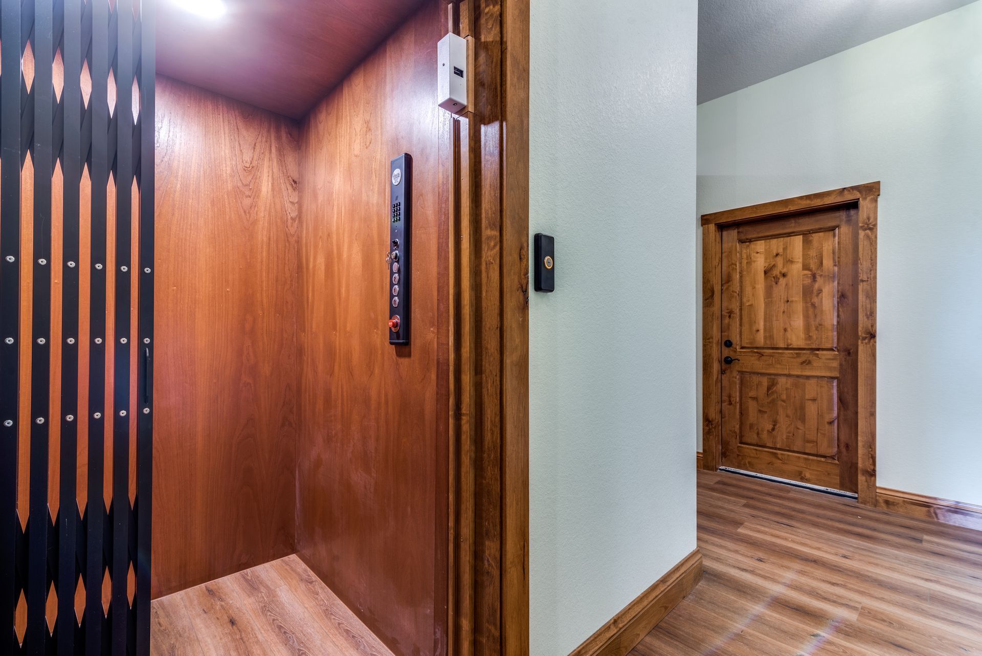A wooden elevator is in a hallway next to a door.