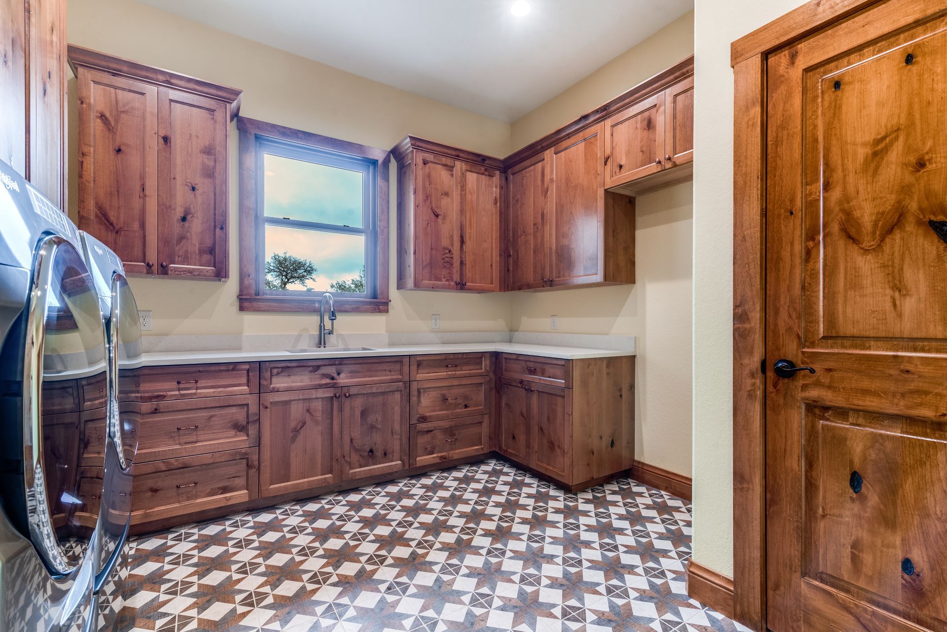 A laundry room with wooden cabinets and a checkered floor.