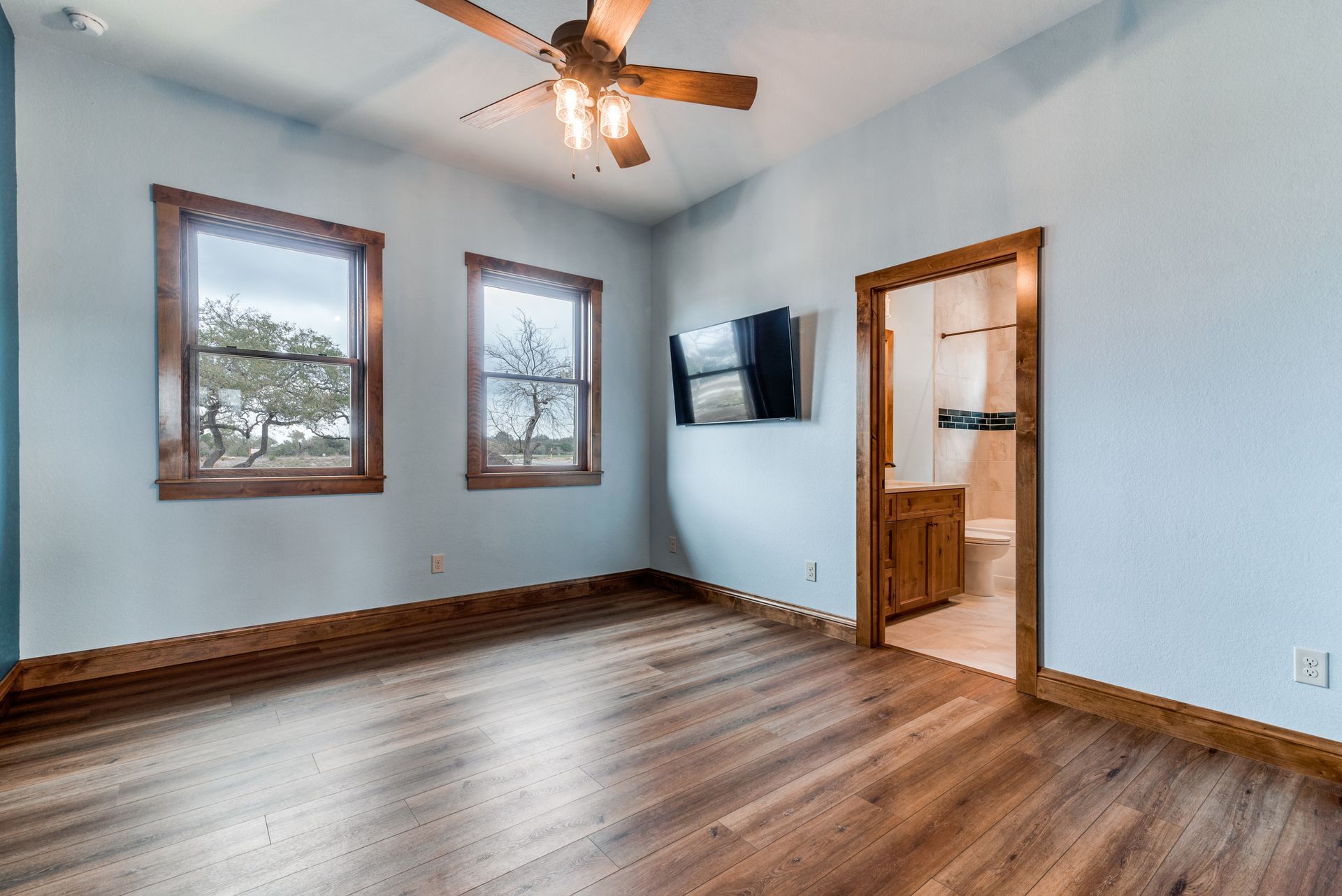 An empty room with hardwood floors and a ceiling fan.