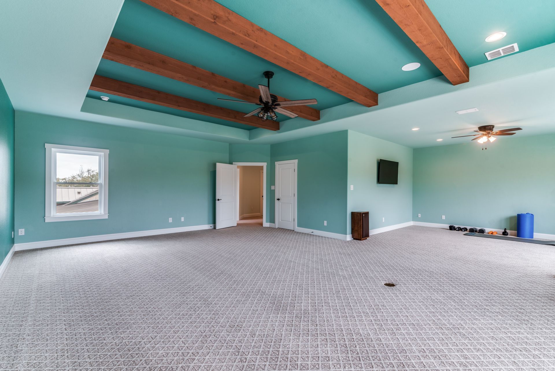 An empty room with blue walls and a ceiling fan.