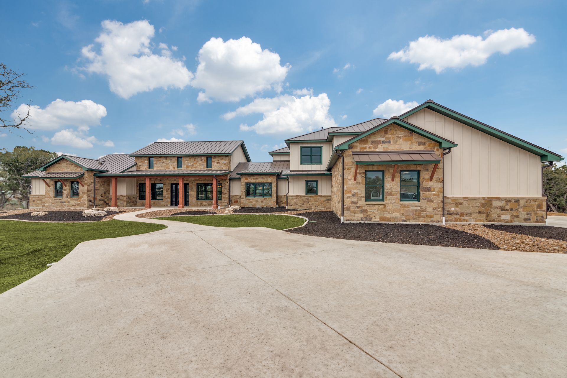 A large house with a lot of windows is sitting on top of a lush green field.