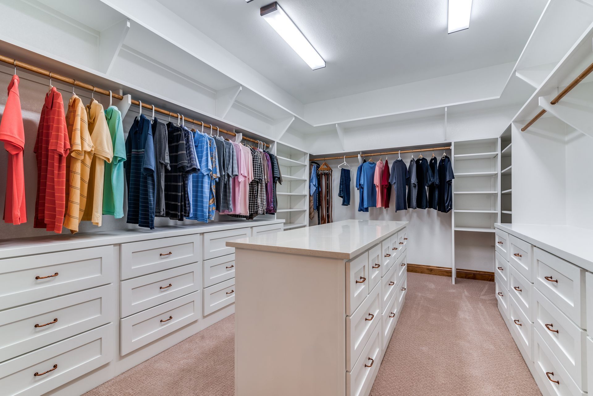 A walk in closet filled with lots of clothes and drawers.