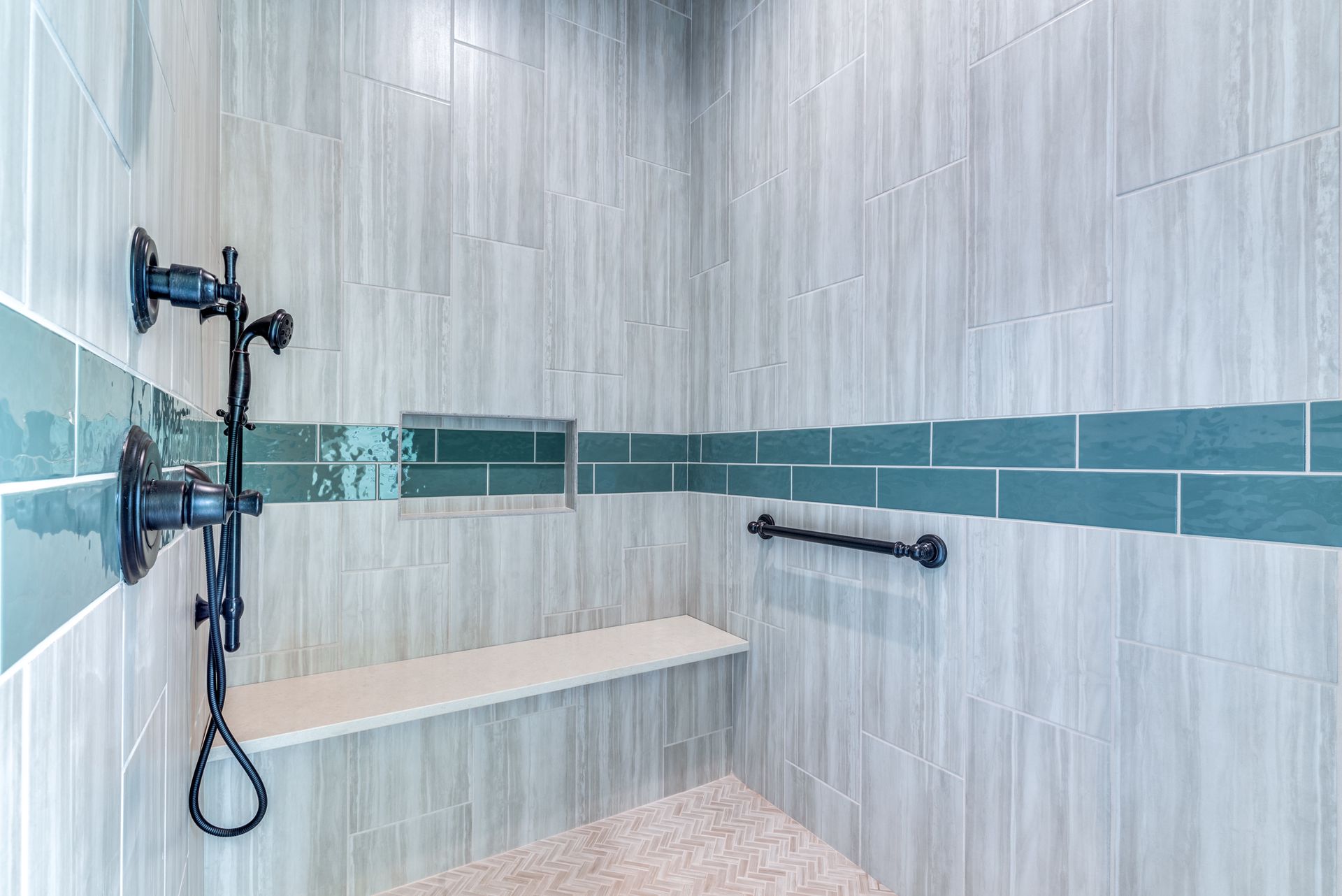 A walk in shower with a bench and a shower head.