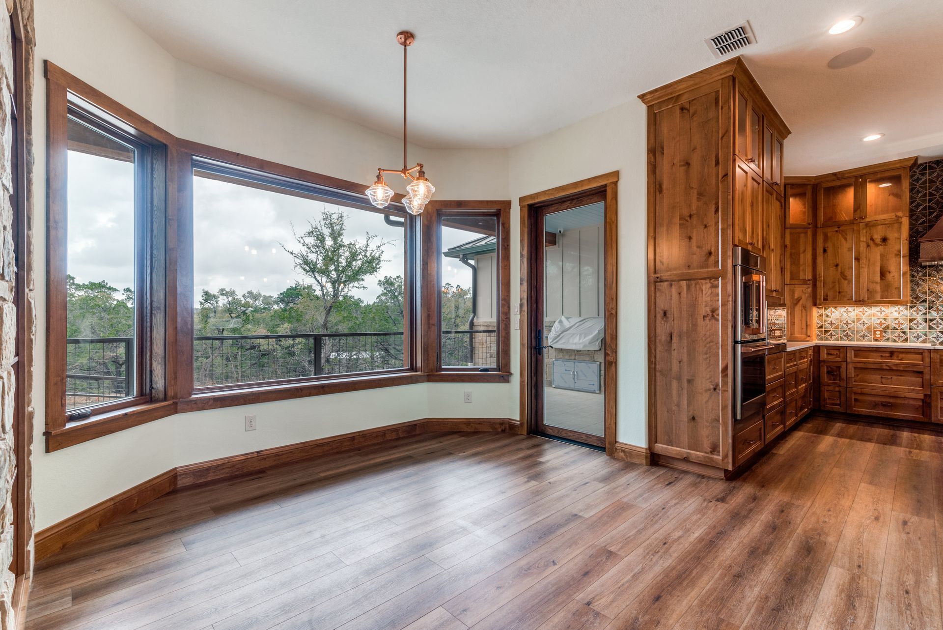 A kitchen and dining room in a house with hardwood floors and lots of windows.