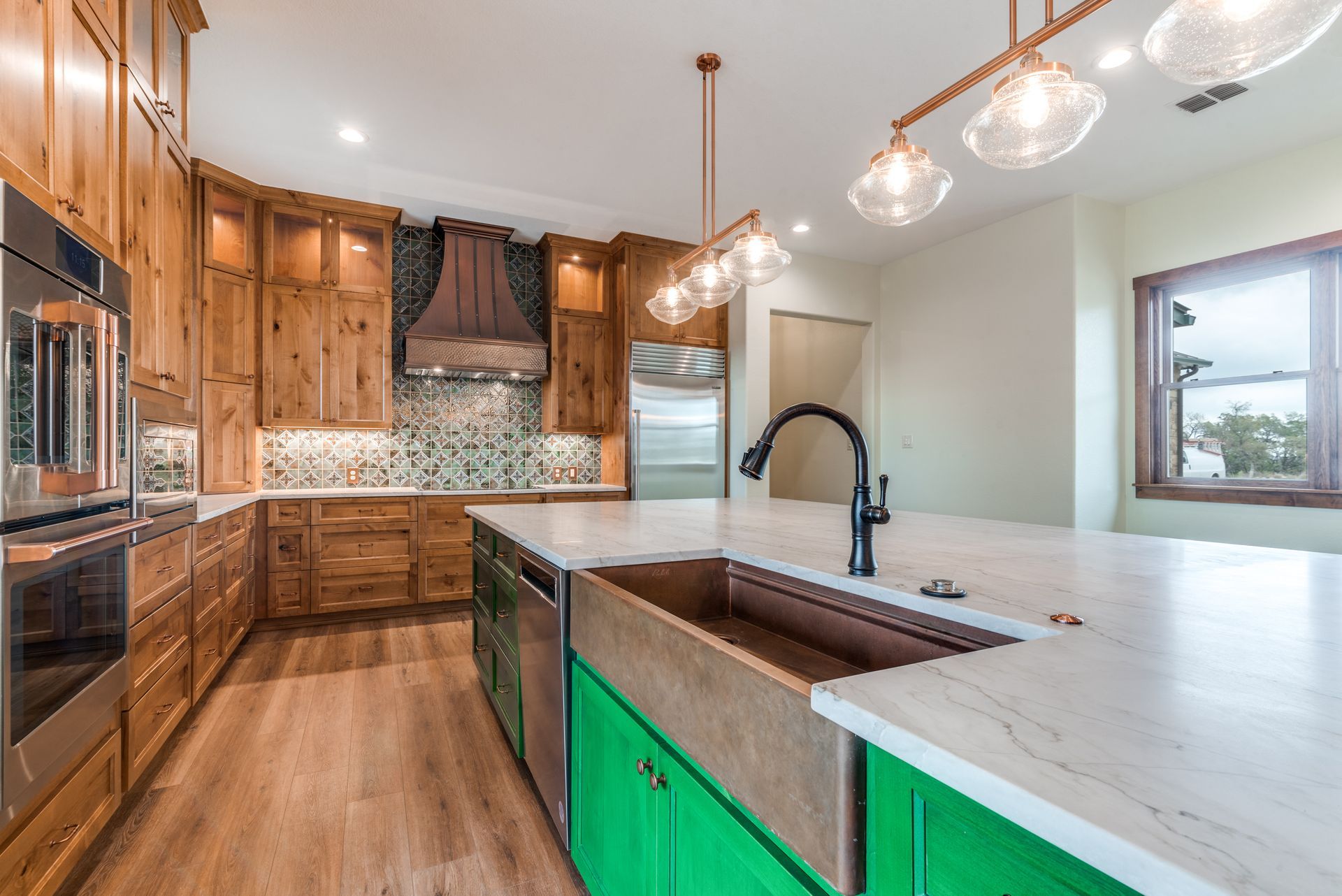 A kitchen with green cabinets and a copper sink.