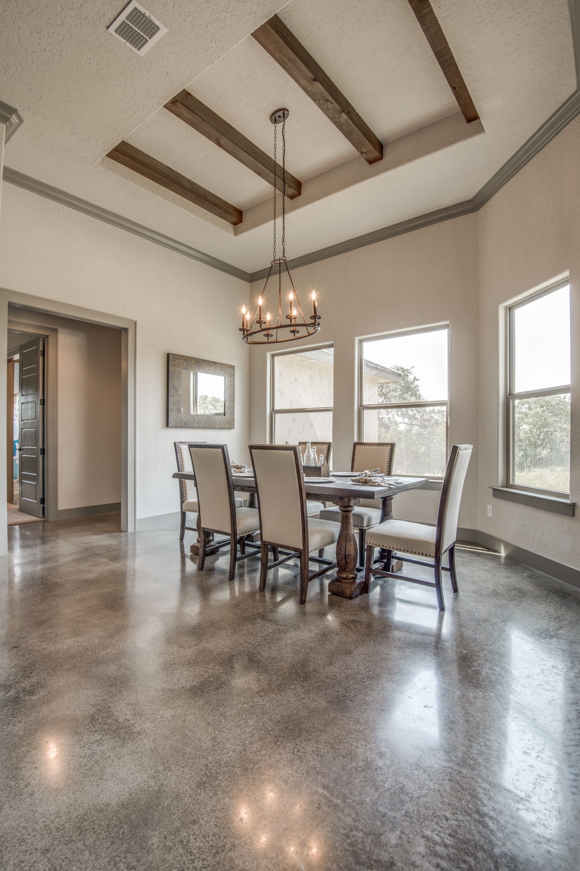 A dining room with a table and chairs and a chandelier hanging from the ceiling.