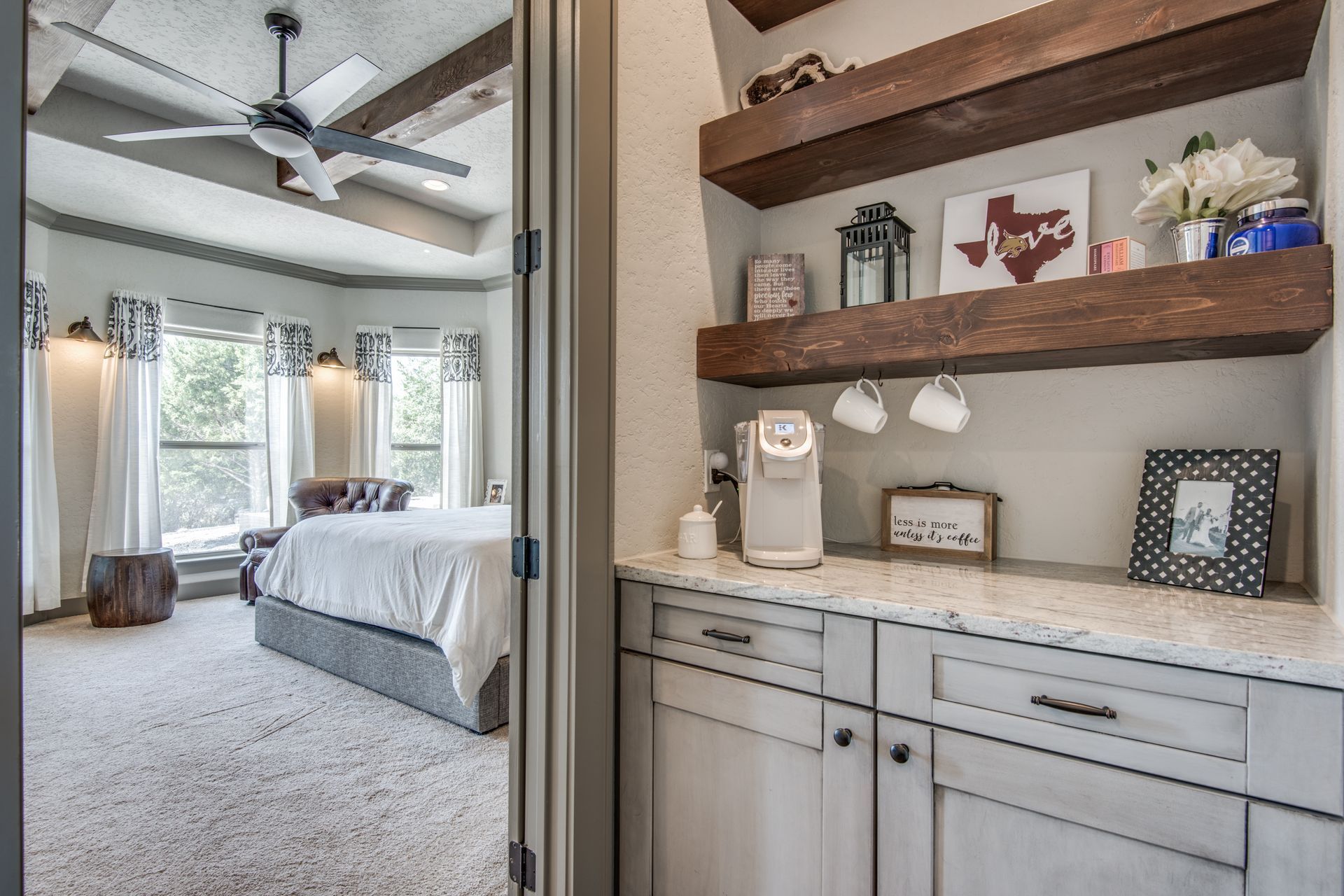 A bedroom with a ceiling fan and a coffee bar.