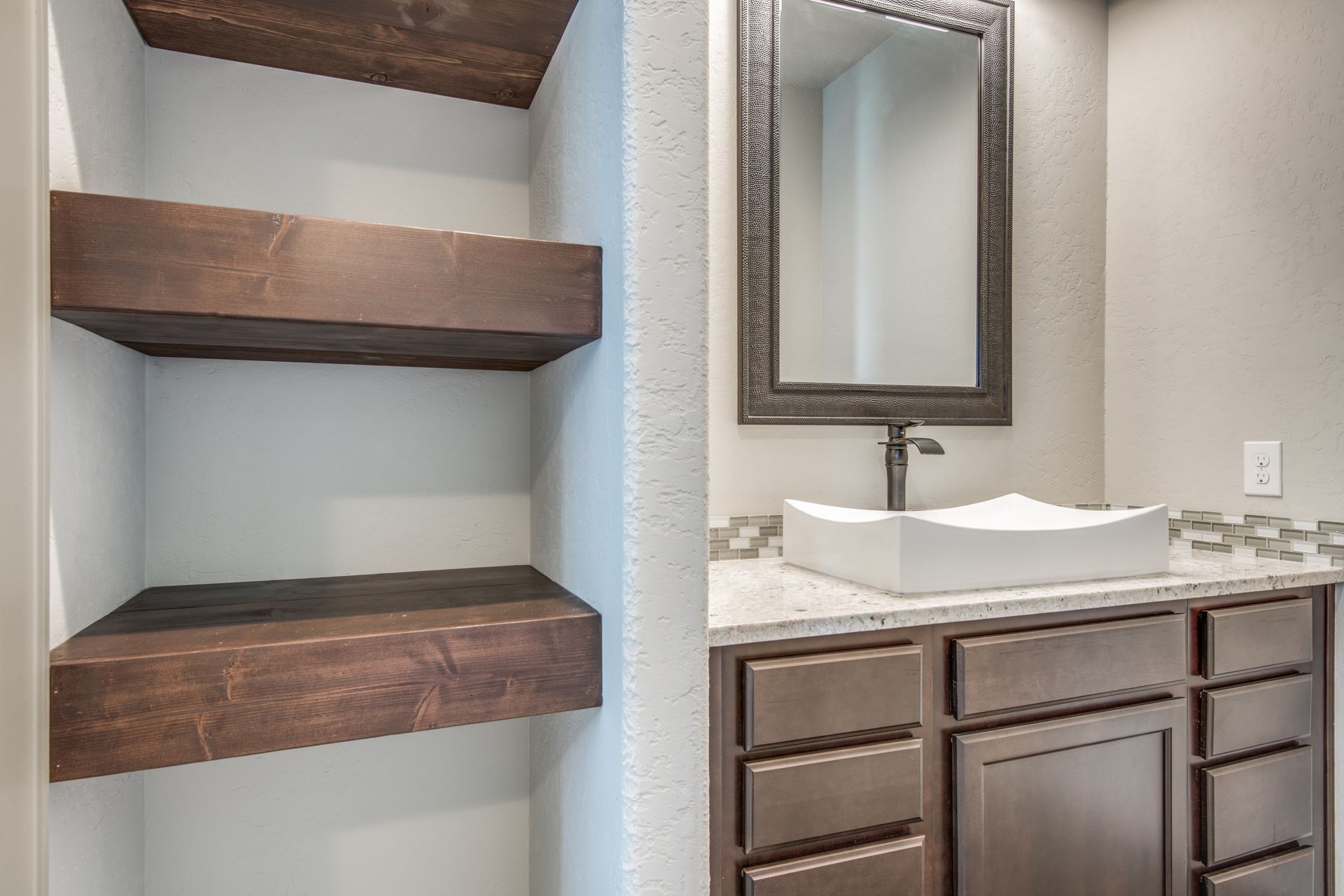 A bathroom with a sink , mirror and shelves.
