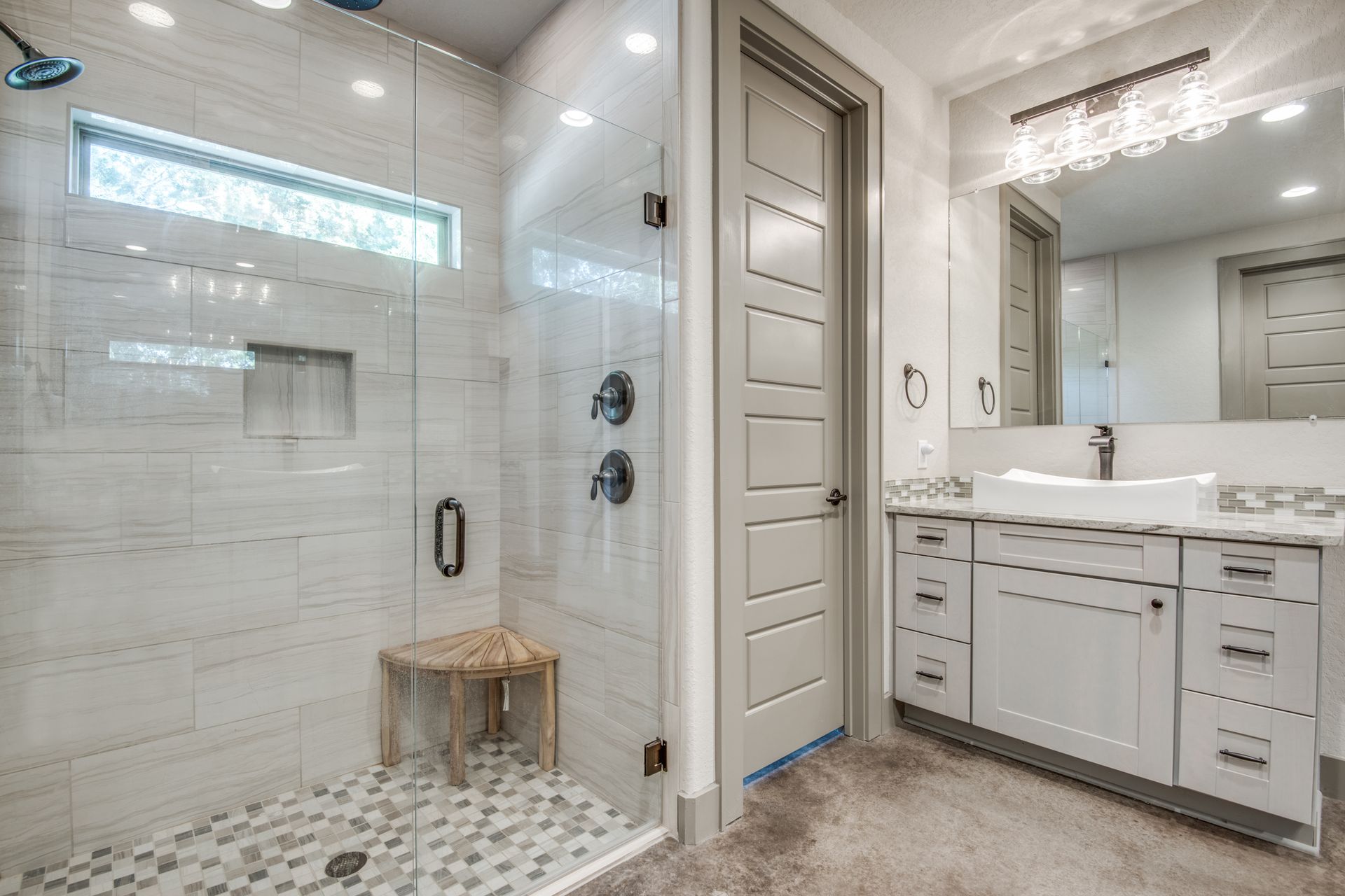 A bathroom with a walk in shower , sink and mirror.