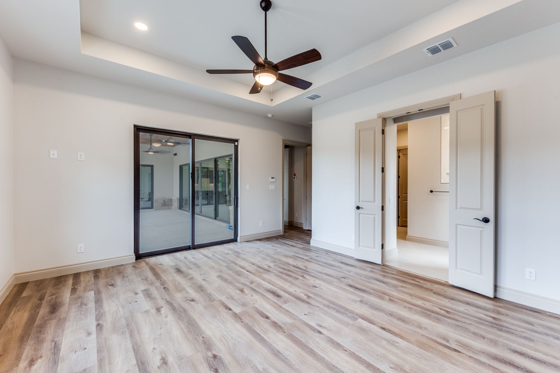 An empty bedroom with hardwood floors and a ceiling fan.