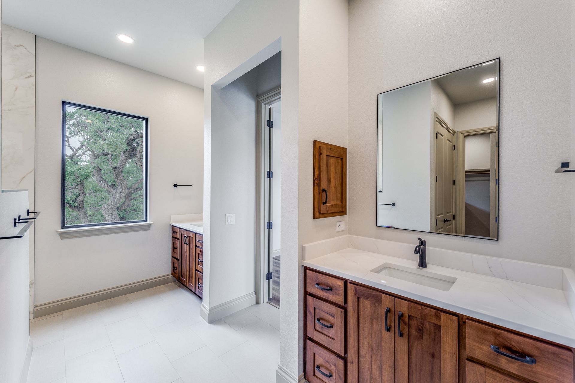 A bathroom with a sink , mirror and window.