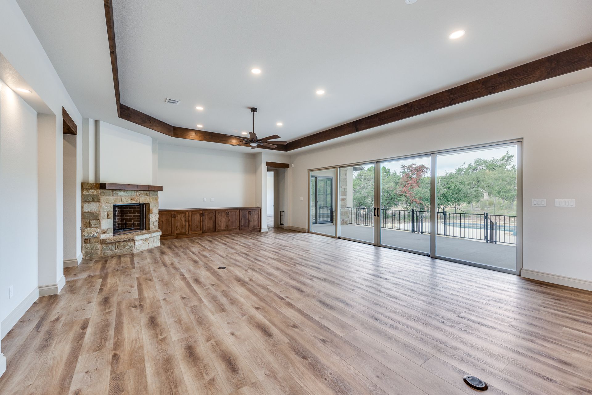 An empty living room with hardwood floors , a fireplace and sliding glass doors.