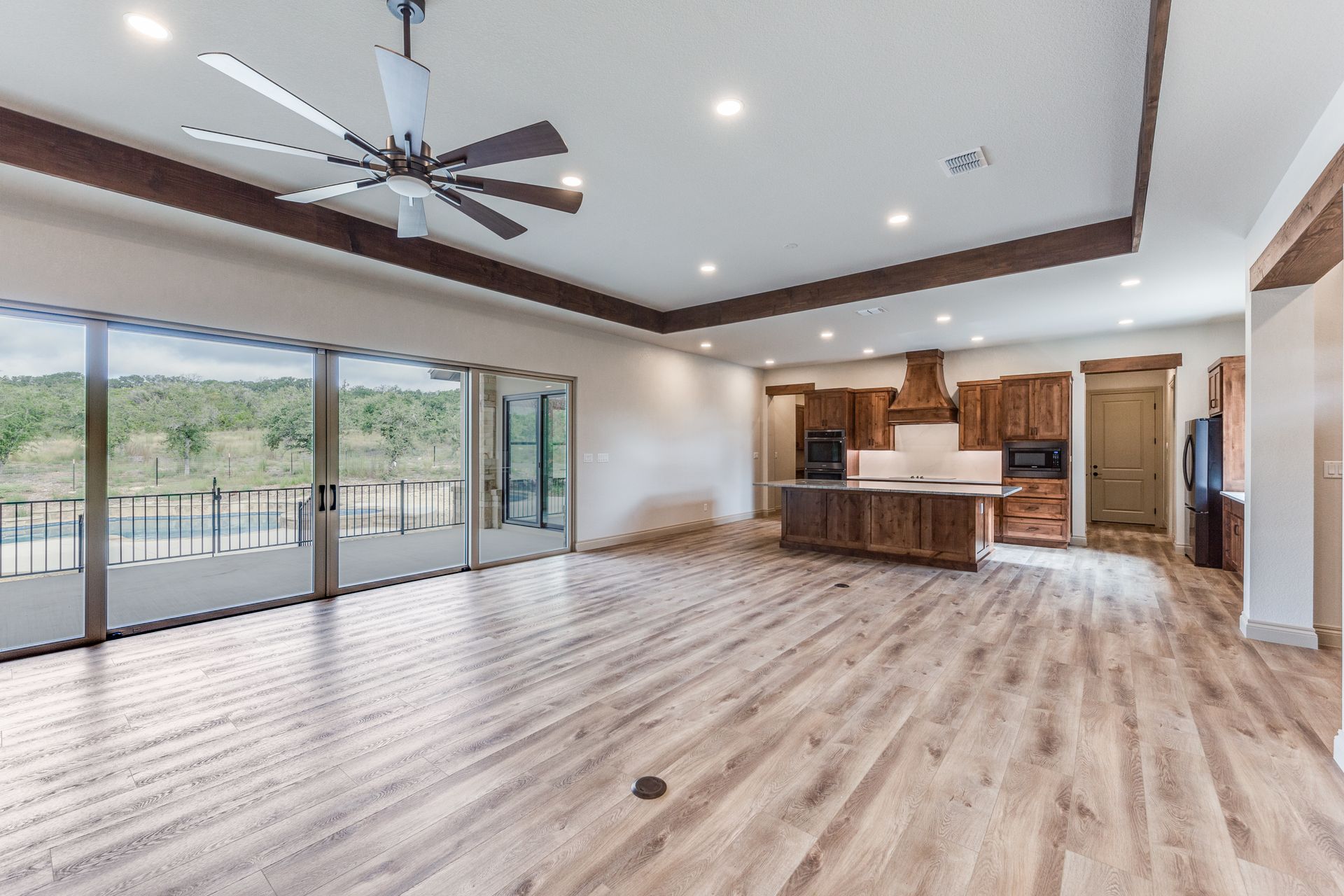 A large empty room with hardwood floors and a ceiling fan.