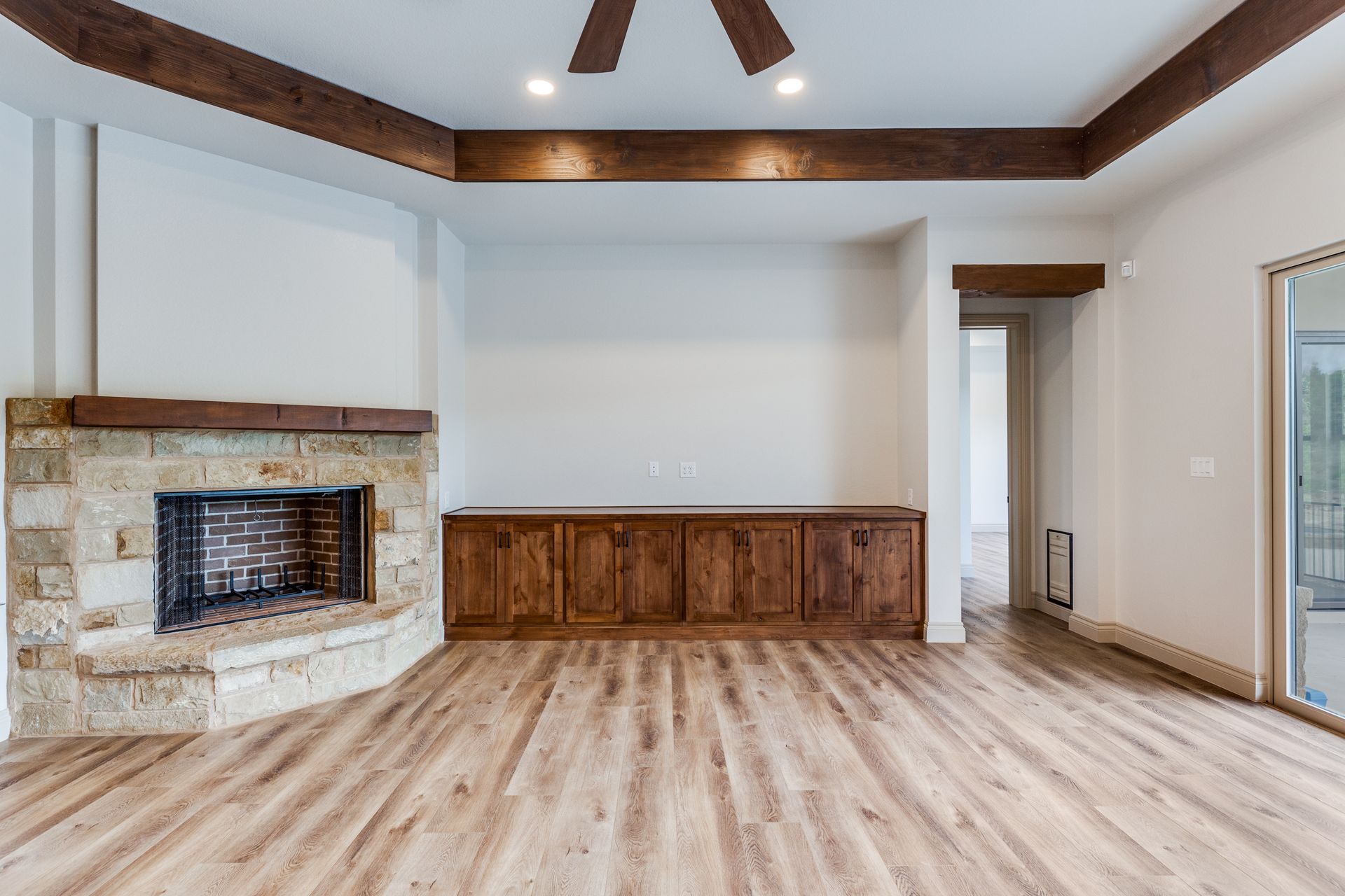 An empty living room with a fireplace and a ceiling fan.