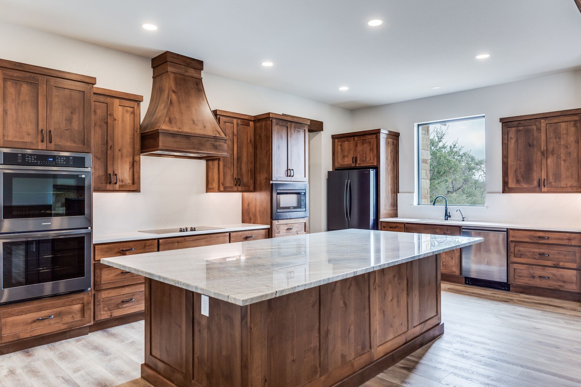 A kitchen with wooden cabinets and a large island in the middle.