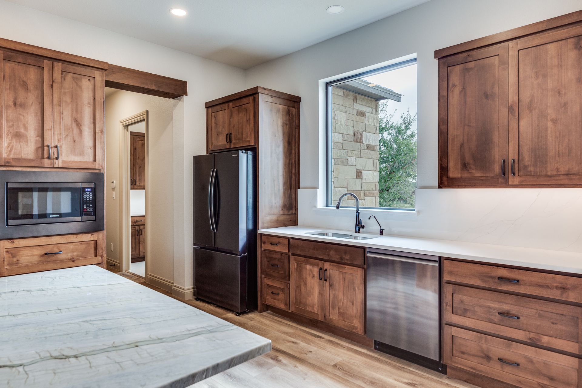 A kitchen with wooden cabinets , stainless steel appliances and a large window.