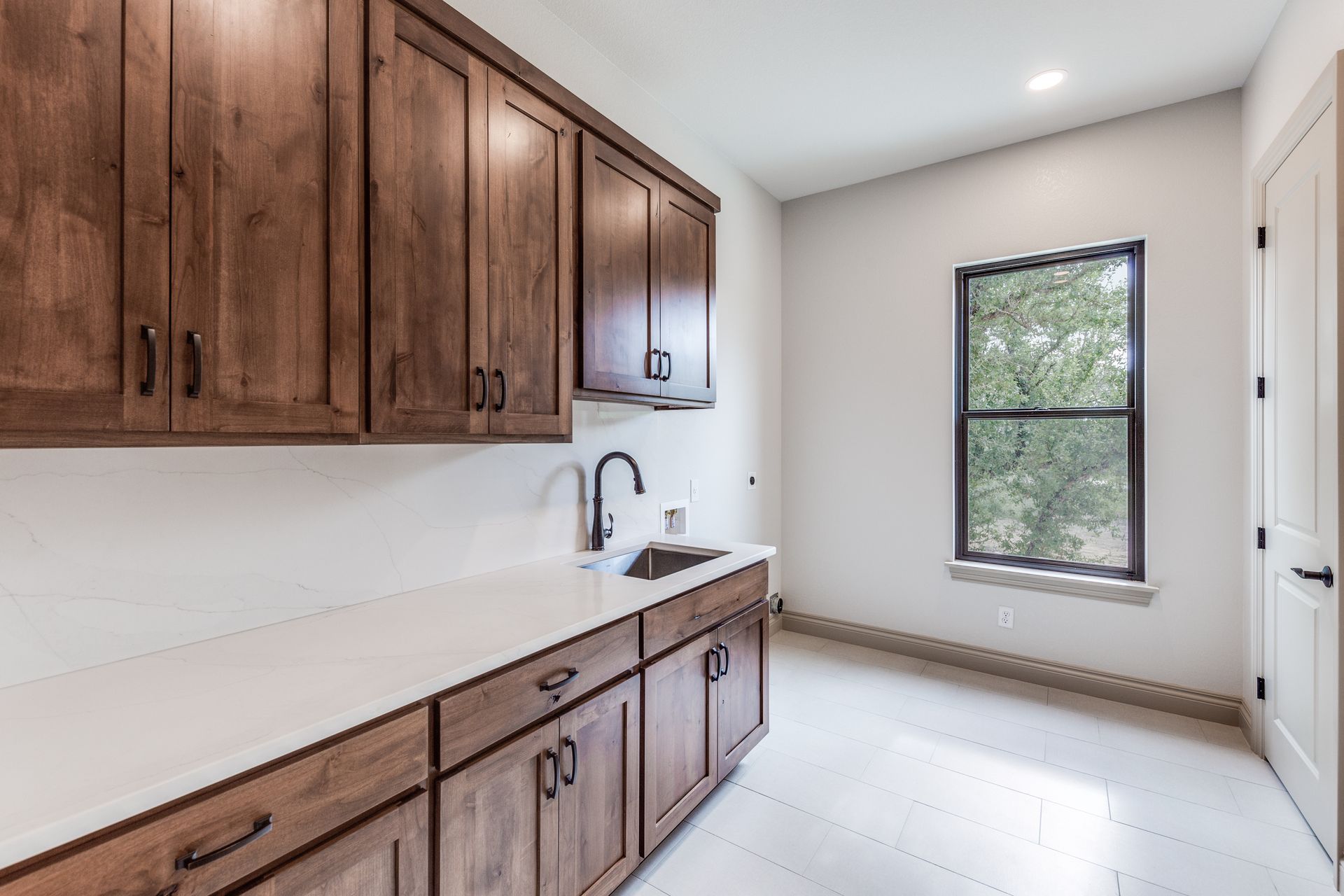 A kitchen with wooden cabinets , a sink , and a window.