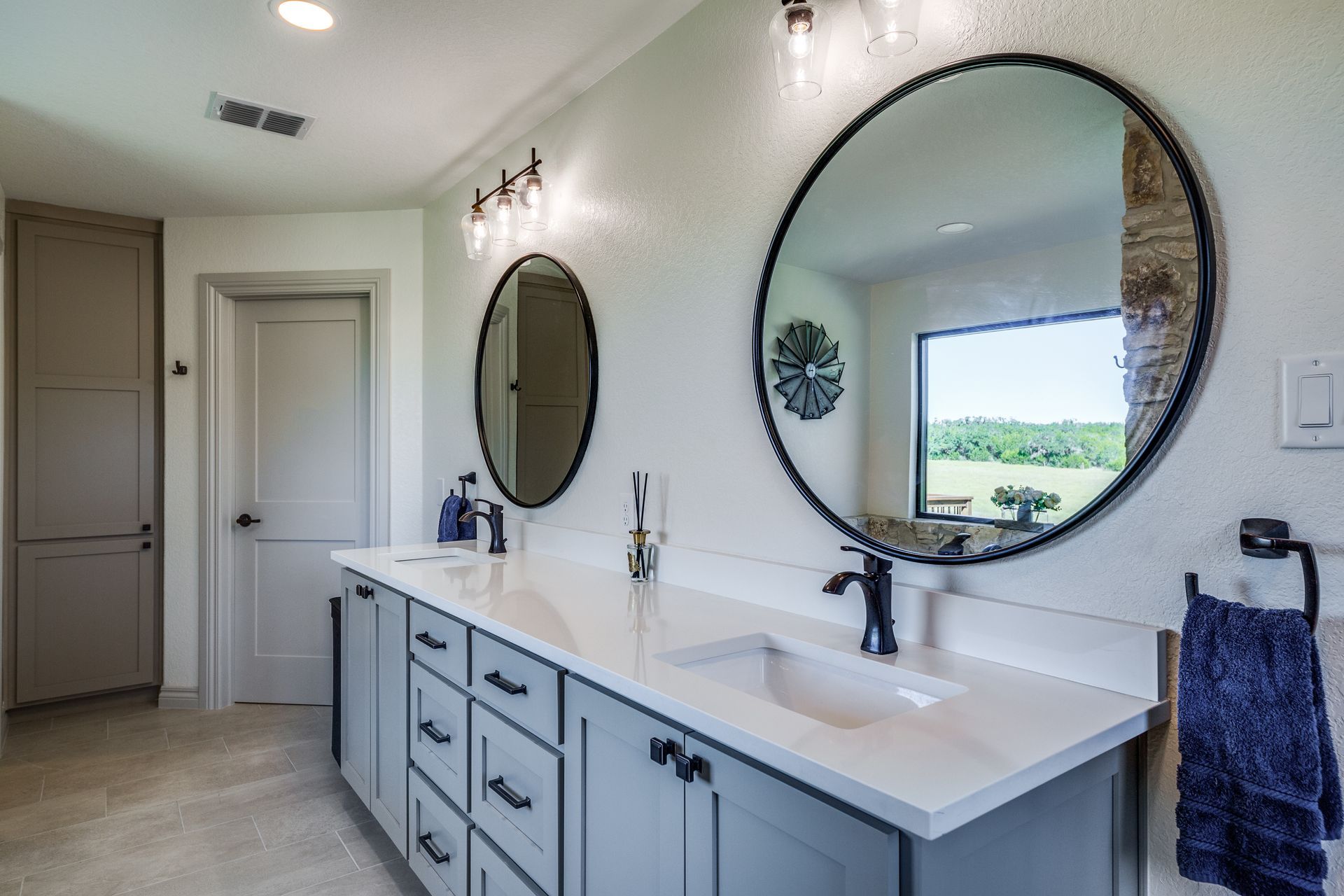 A bathroom with two sinks and two round mirrors.