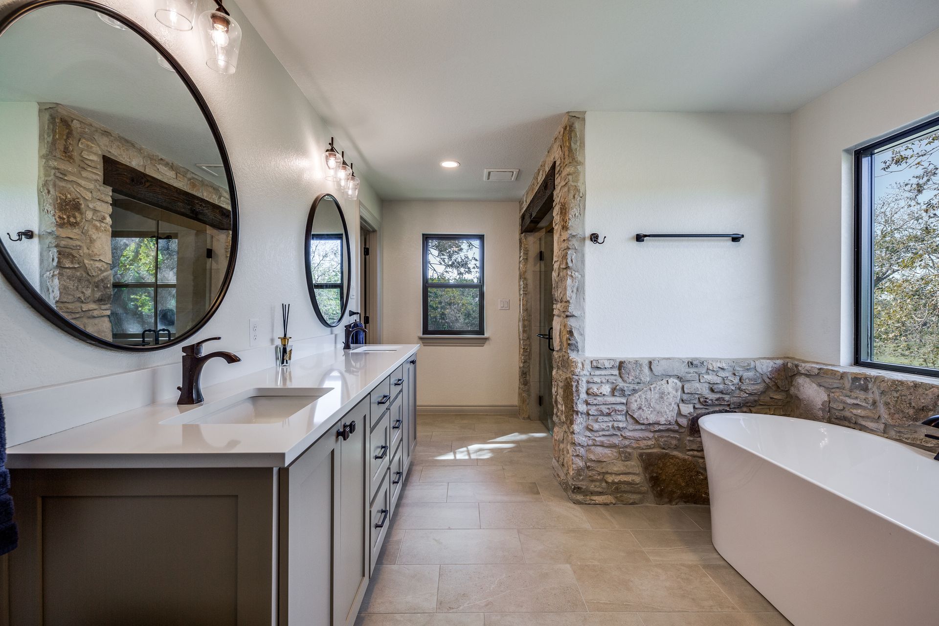 A bathroom with two sinks , a tub , and two mirrors.