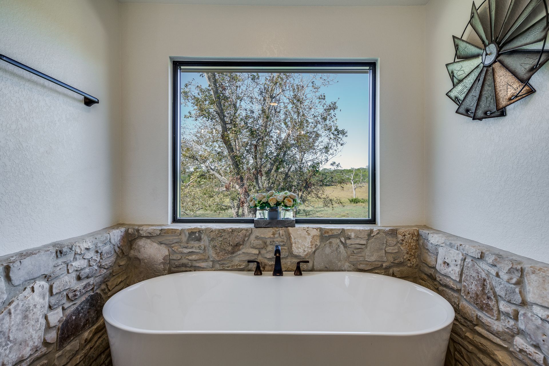 A bathroom with a tub and a window with a windmill on the wall.