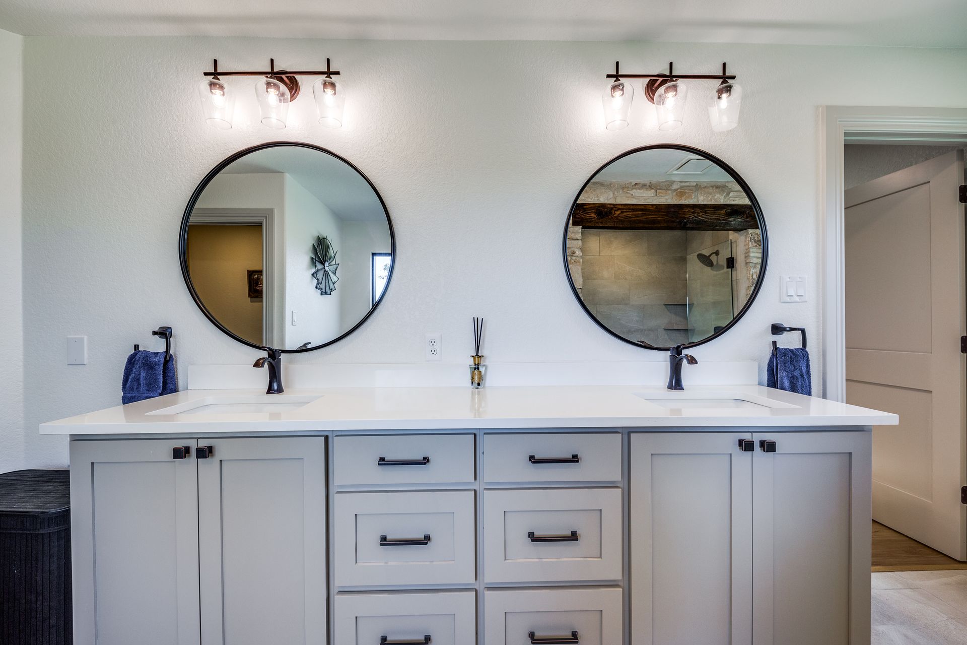 A bathroom with two sinks and two round mirrors.