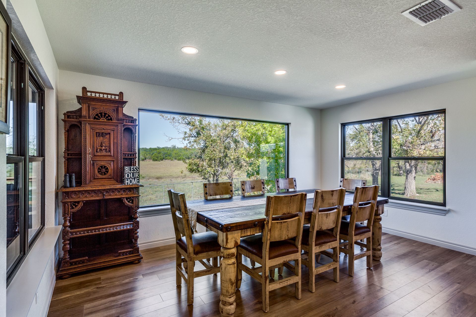A dining room with a long wooden table and chairs and a large window.