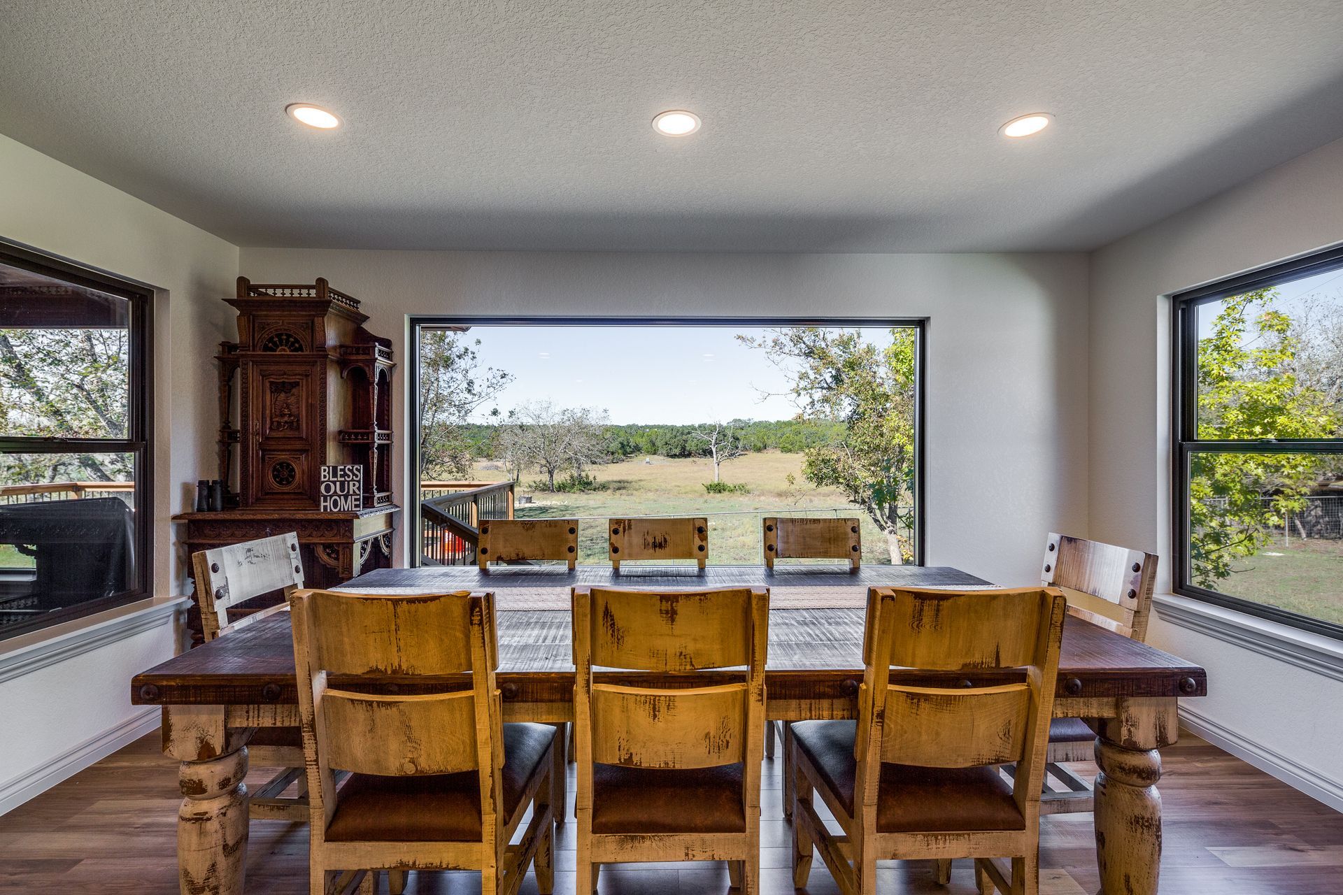 A dining room with a table and chairs and a view of a field.