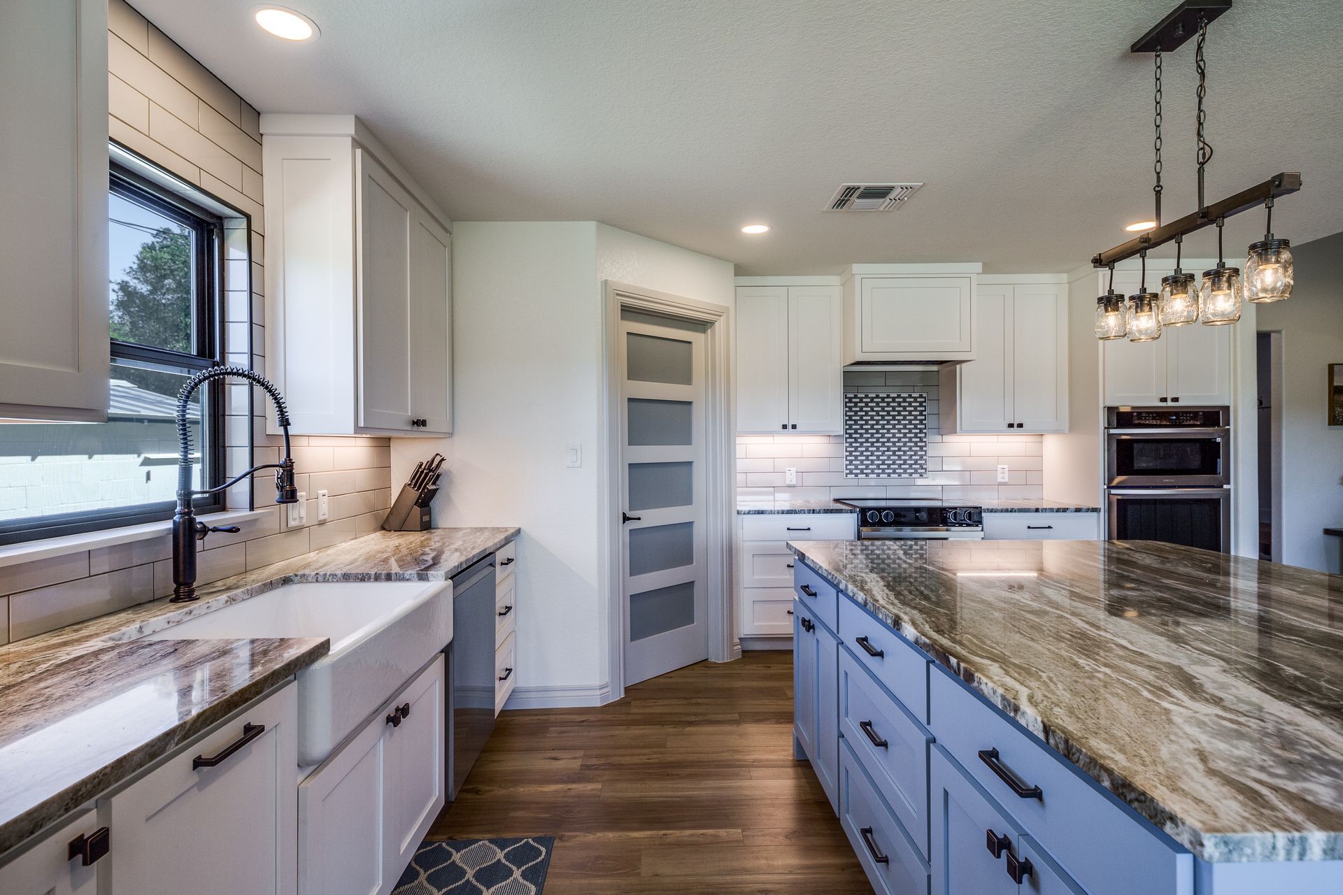 A kitchen with white cabinets , granite counter tops , stainless steel appliances and a large island.