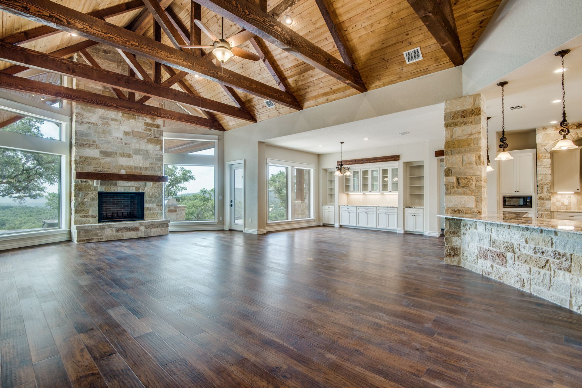 A large empty living room with hardwood floors and a ceiling fan.