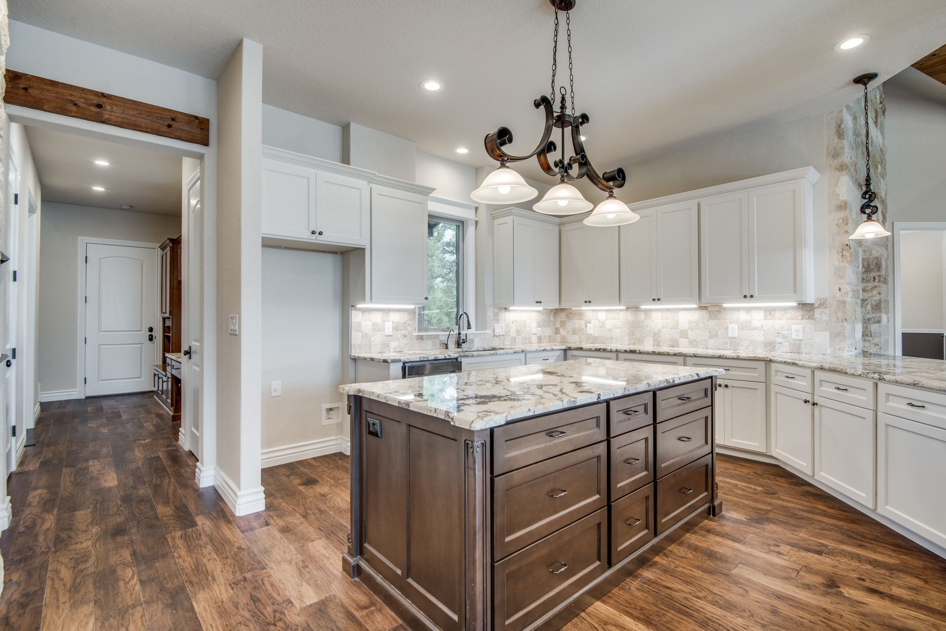 A kitchen with white cabinets and a large island in the middle.