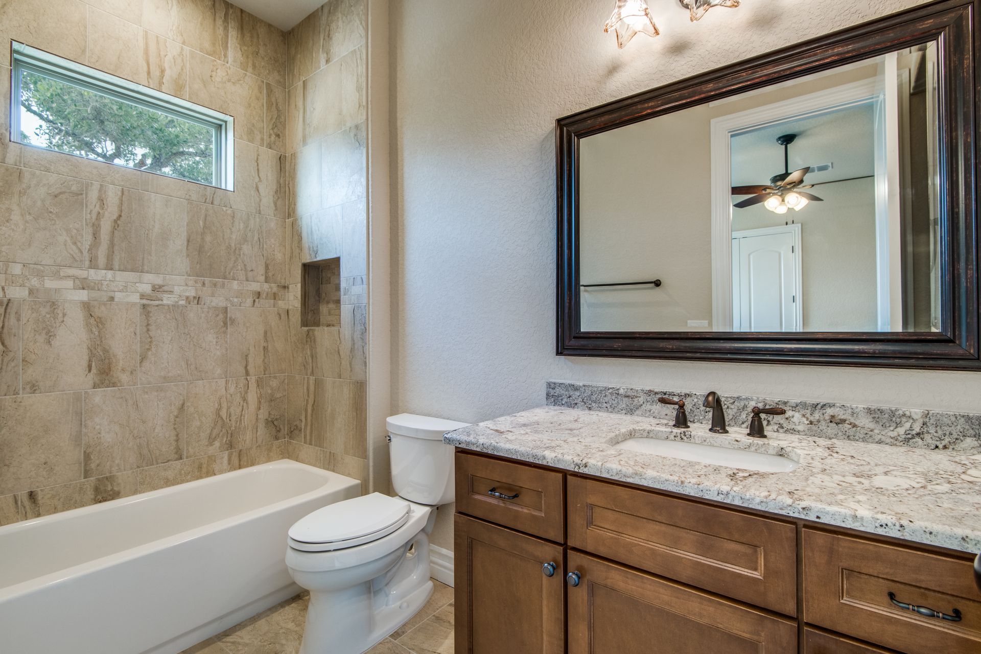 A bathroom with a toilet , sink , tub and mirror.