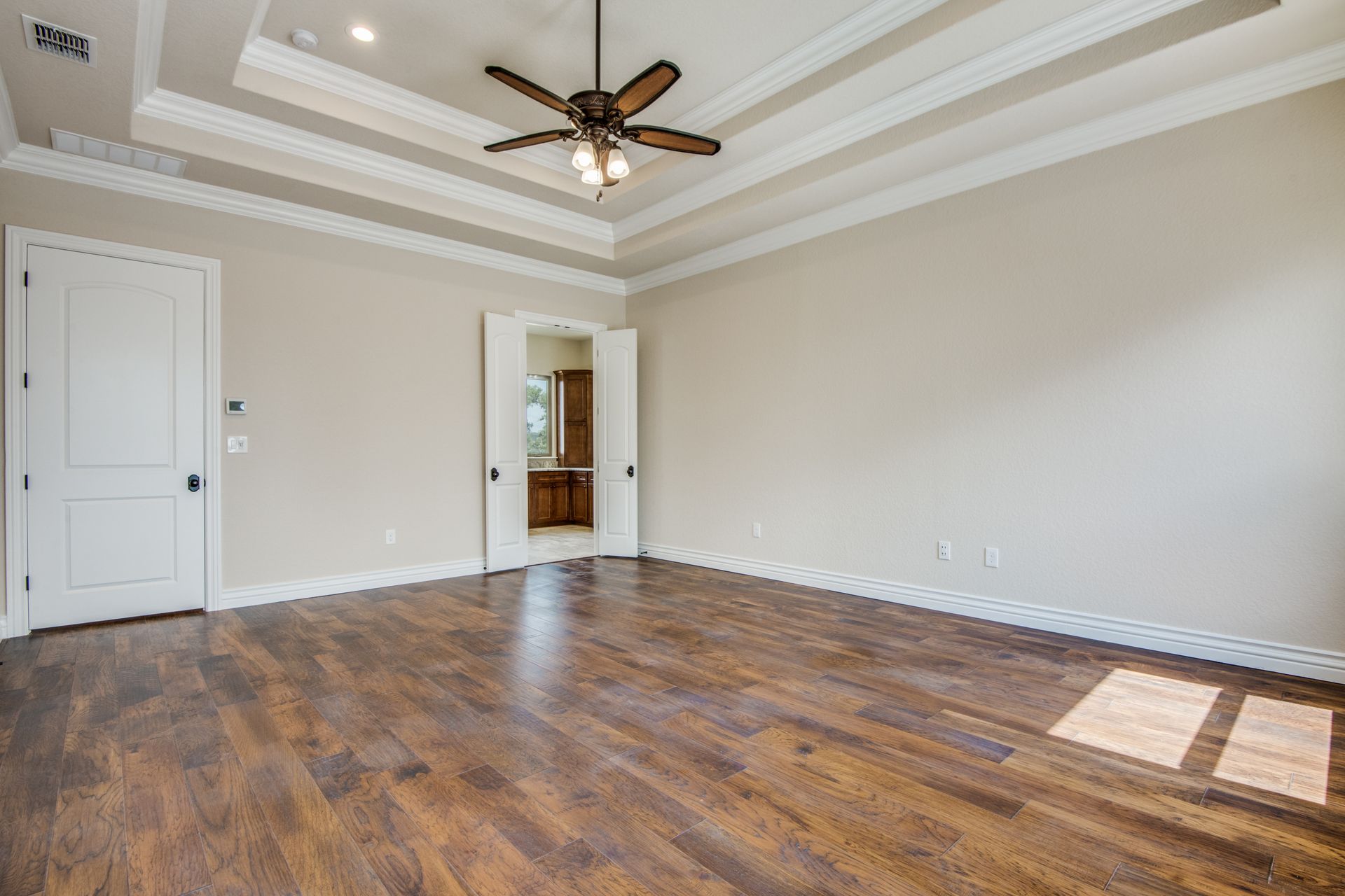 A large empty room with hardwood floors and a ceiling fan.