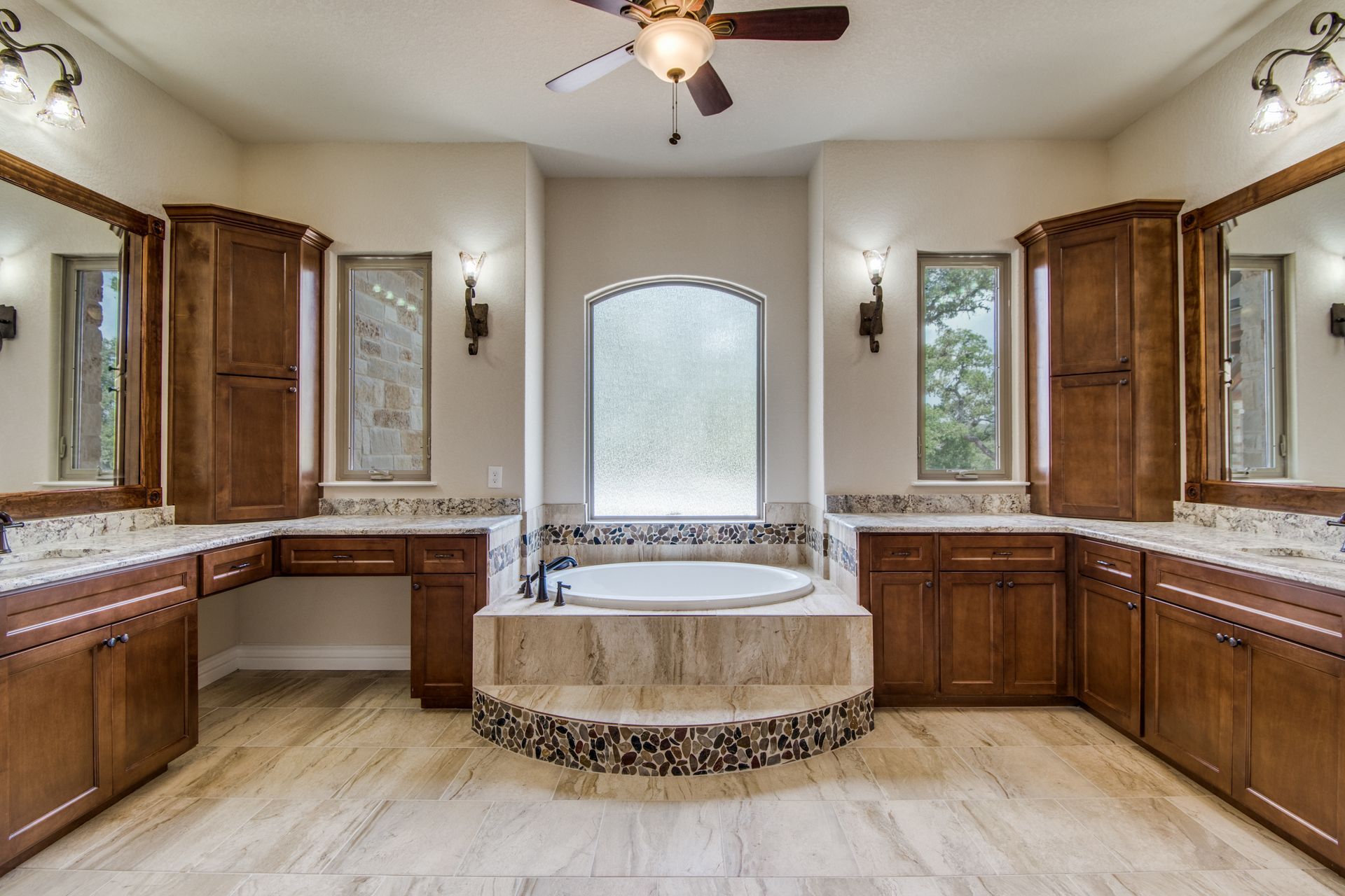 A bathroom with two sinks , a tub and a ceiling fan.