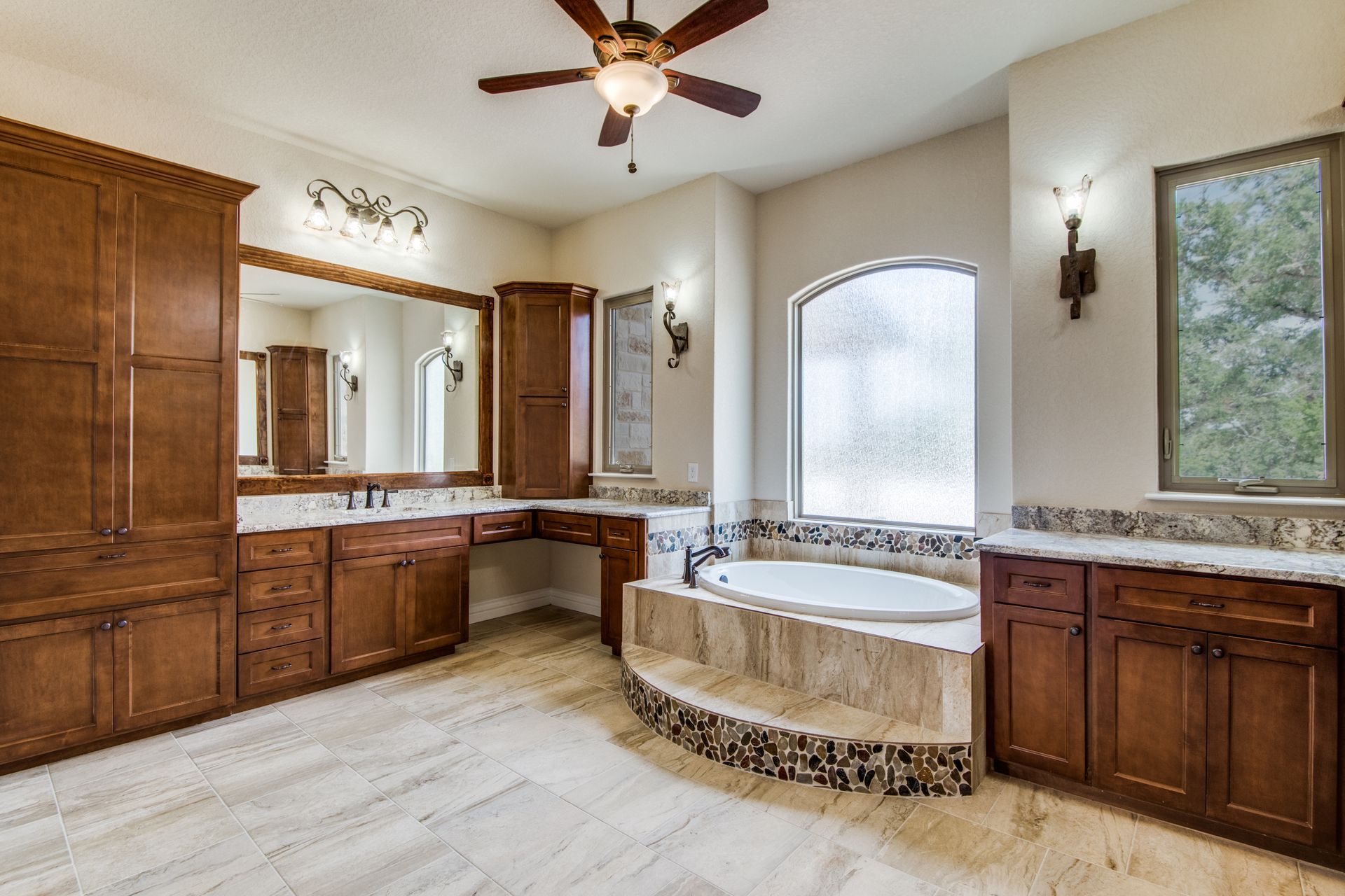 A bathroom with two sinks , a tub and a ceiling fan.