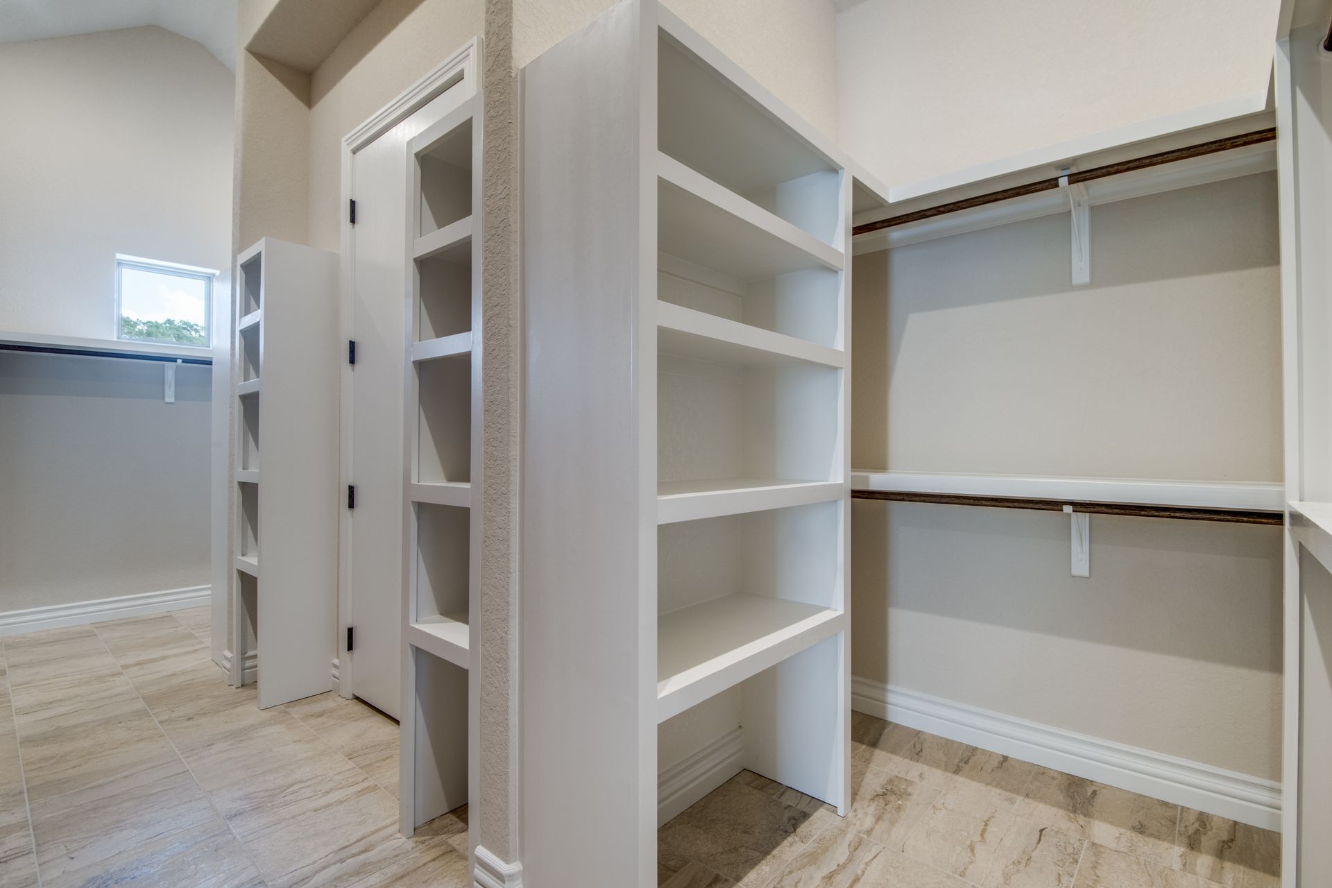 A walk in closet with lots of shelves and a mirror.